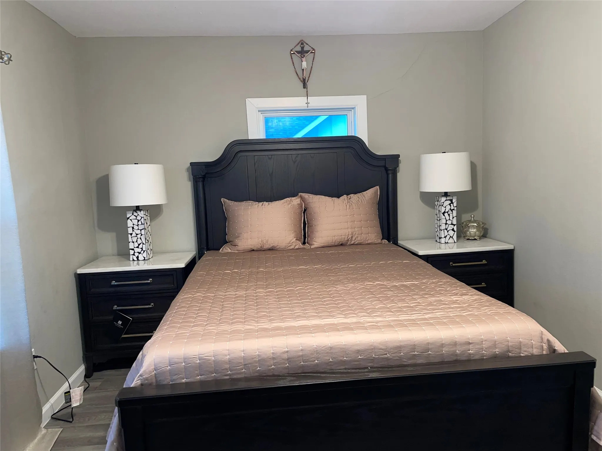 Bedroom featuring a dark wood bed frame with a tall headboard, two matching nightstands with white countertops, and light gray wall paint
