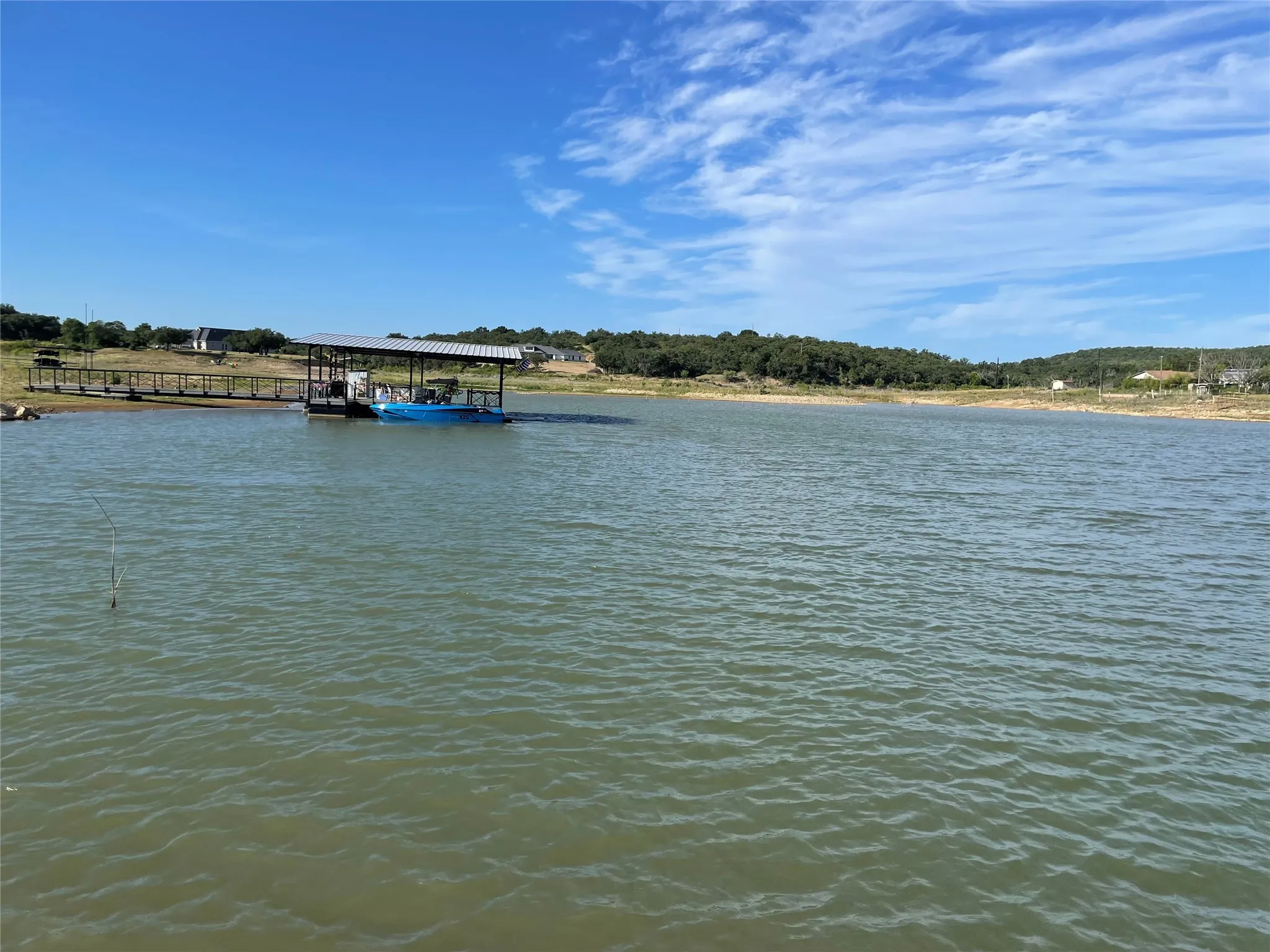 Waterfront property featuring a private boat dock with a covered slip and extended wooden walkway