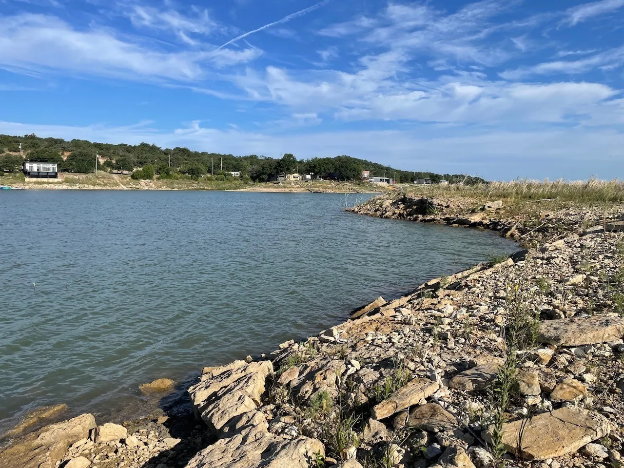 Waterfront property featuring a natural rock shoreline and distant treed hills