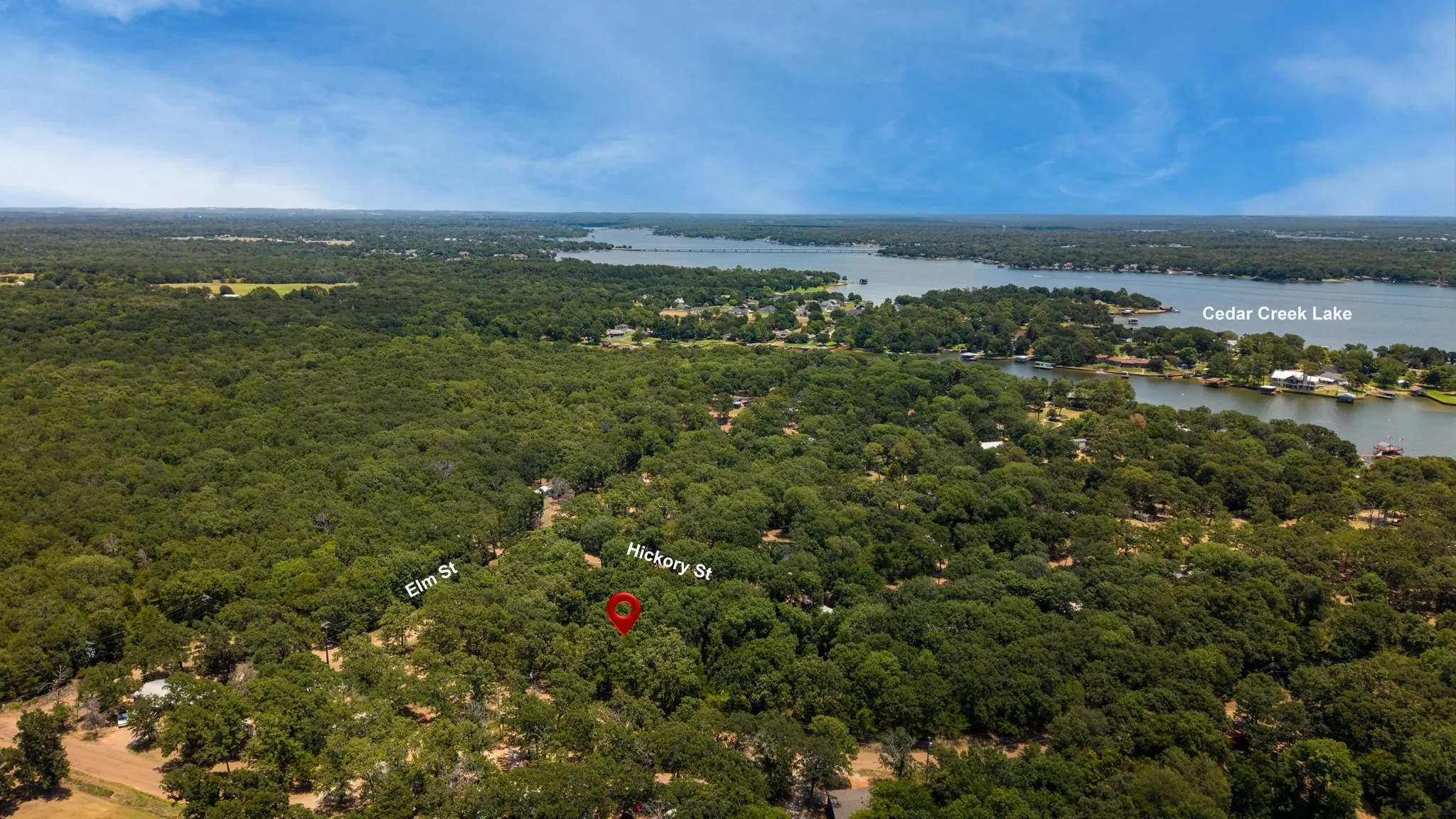 Aerial perspective highlighting Cedar Creek Lake, dense tree coverage, and a residential area