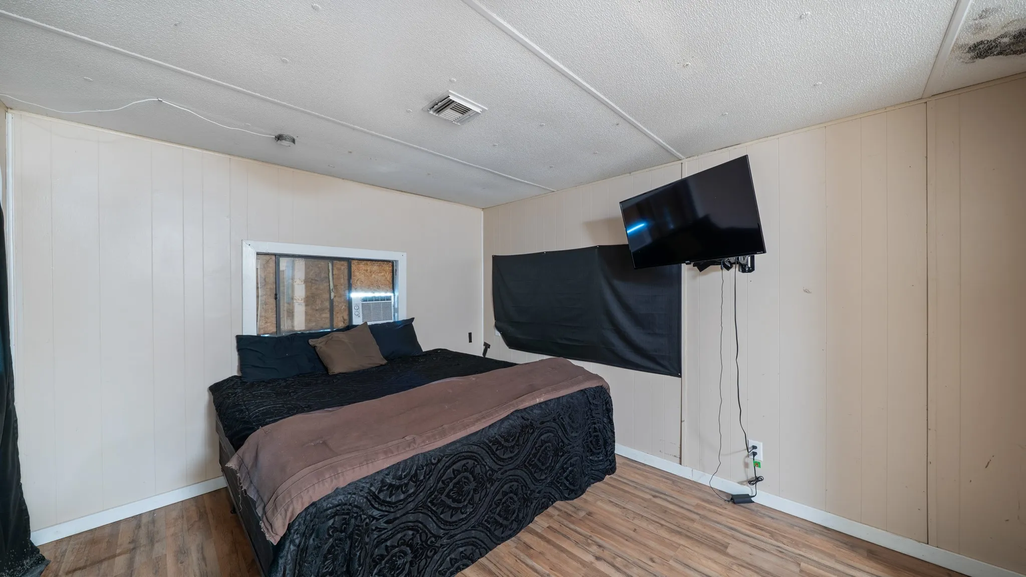 Wood-finish flooring with light-toned wall panels, featuring a wall-mounted window air conditioning unit