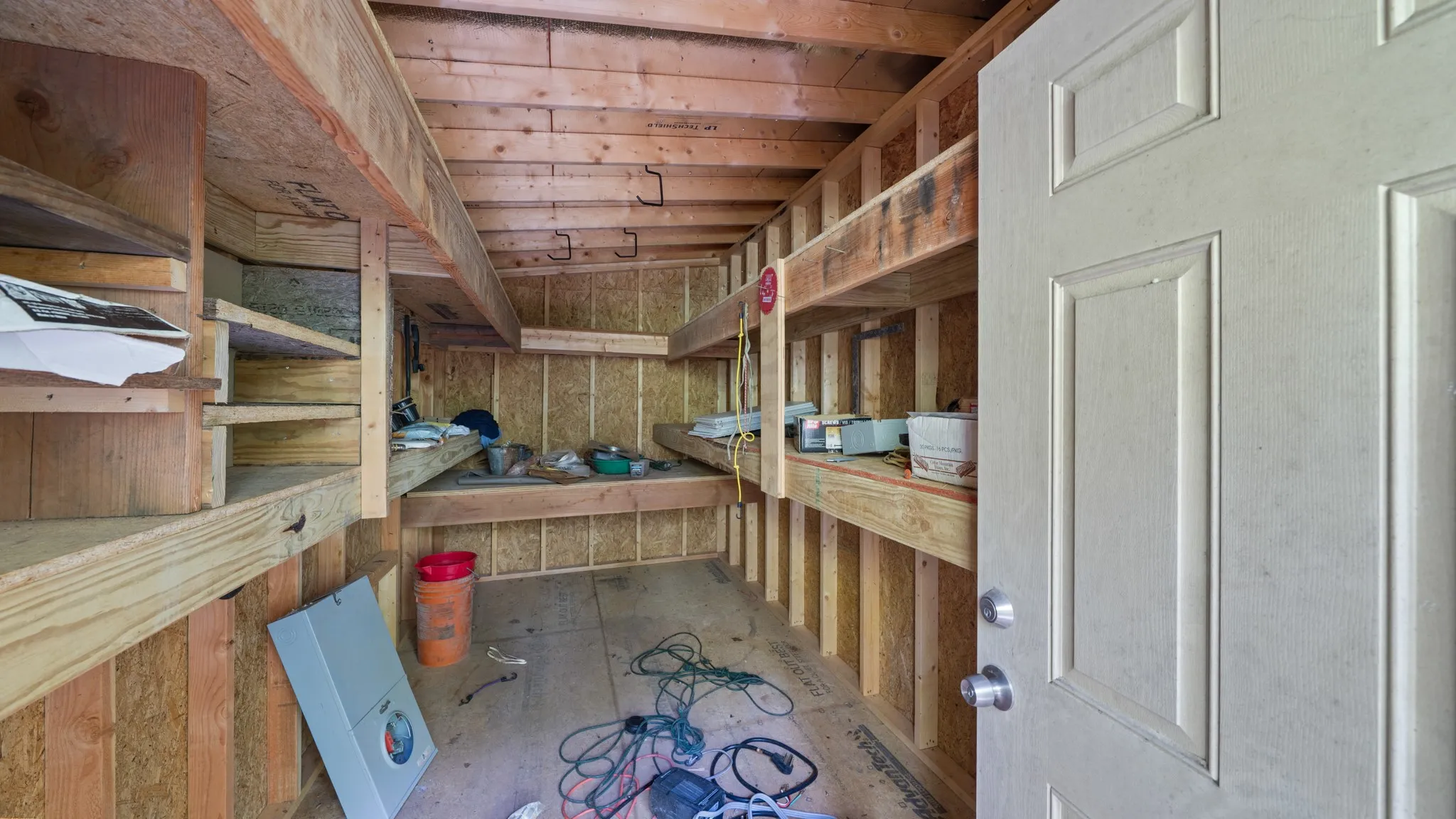 Interior space featuring exposed wood framing, built-in shelving, and a paneled door