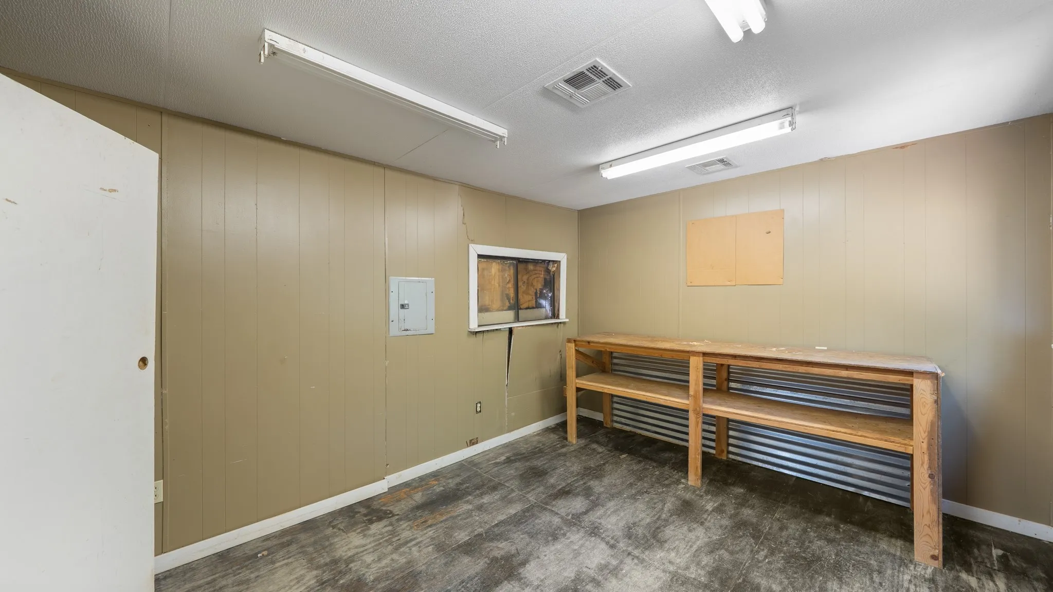 Utility space featuring a built-in wooden workbench, corrugated metal shelving, and panel walls