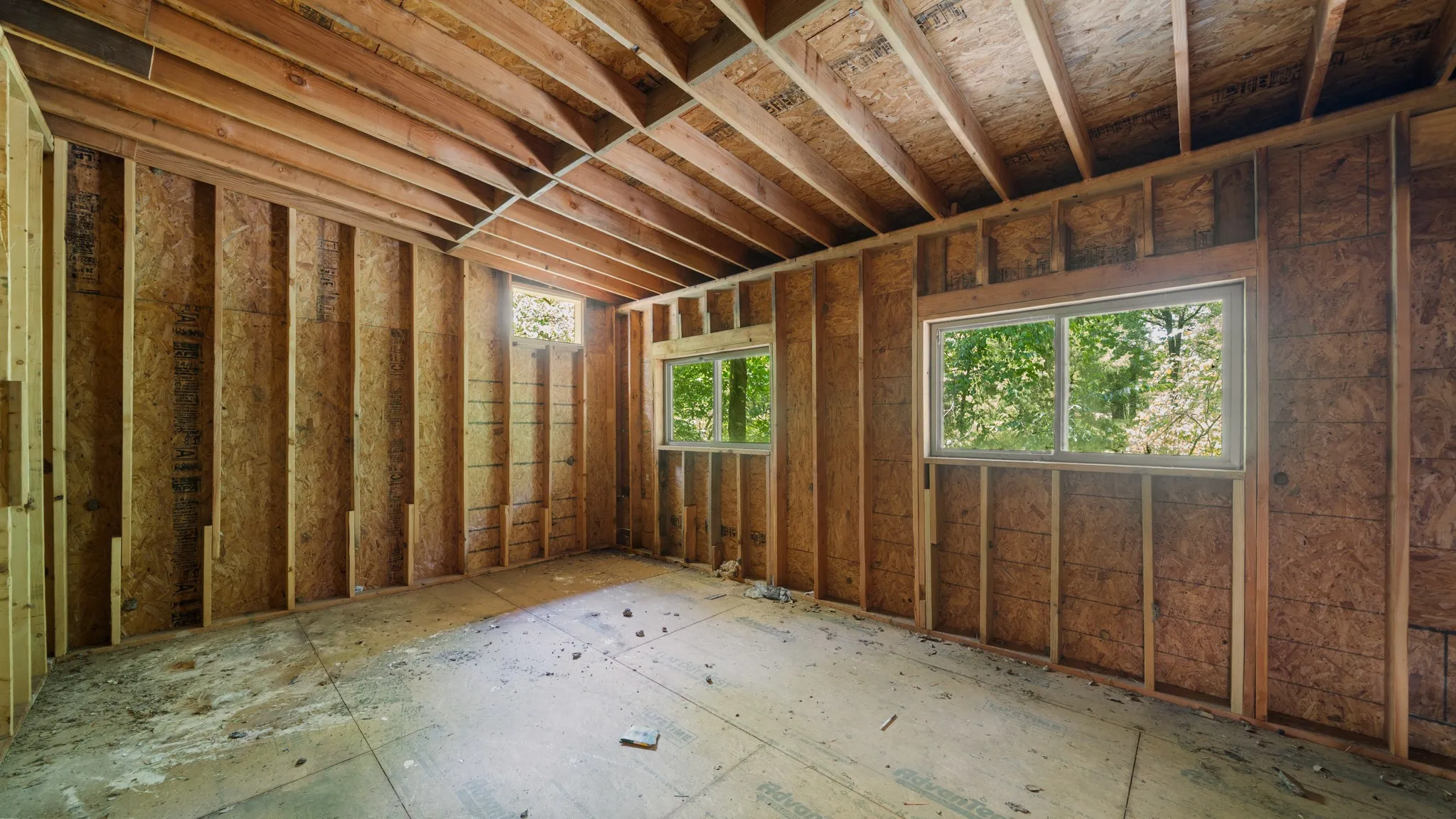Framed interior space with exposed ceiling joists and two windows