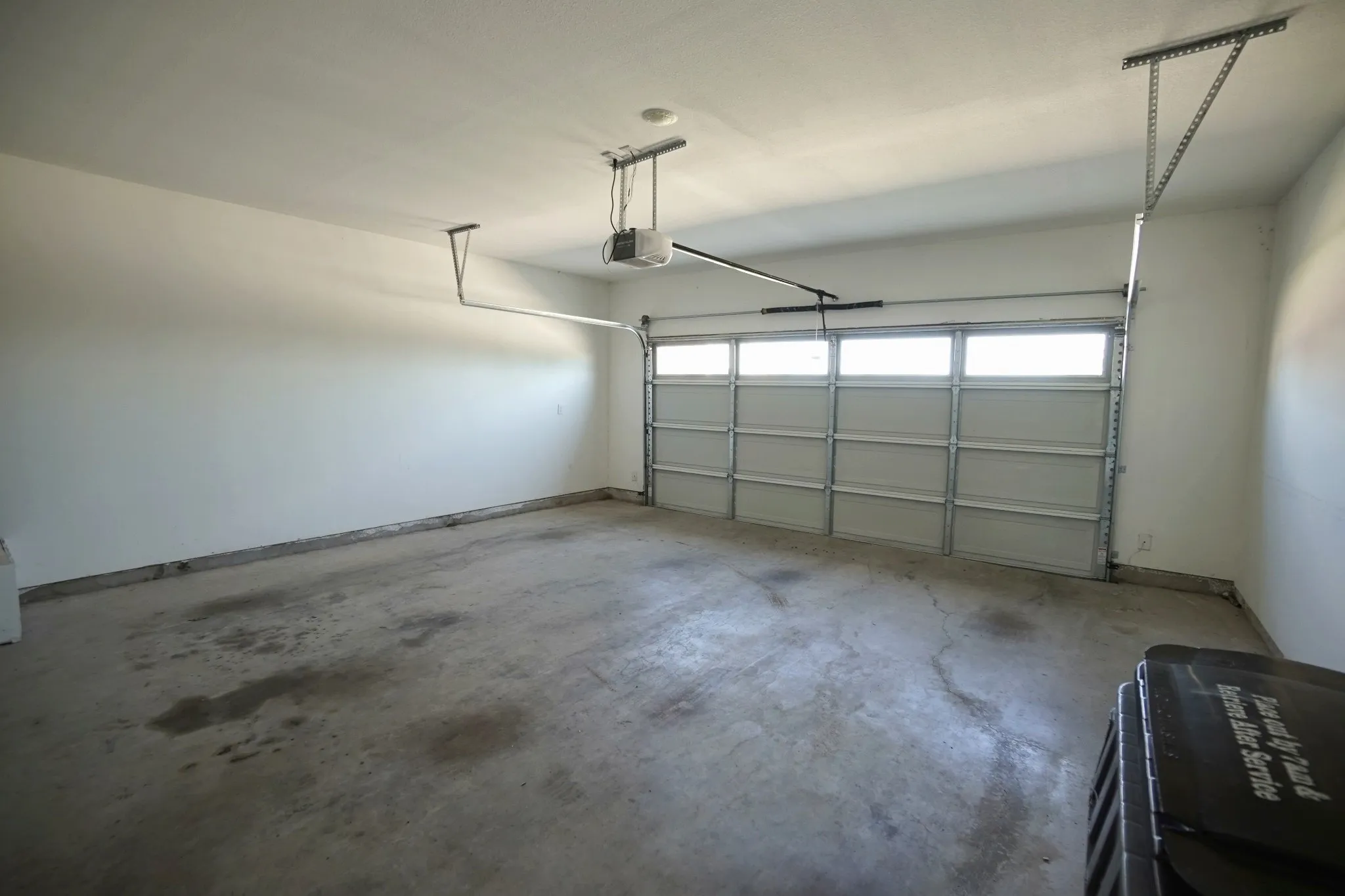 Two-car garage with a sectional garage door featuring upper-level windows, an automatic opener, and painted walls
