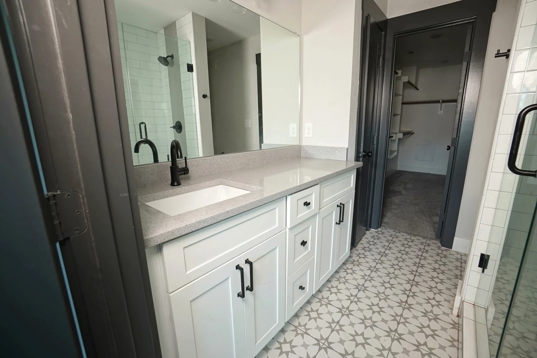 Vanity with white shaker cabinetry, light-toned countertop, and matte black hardware