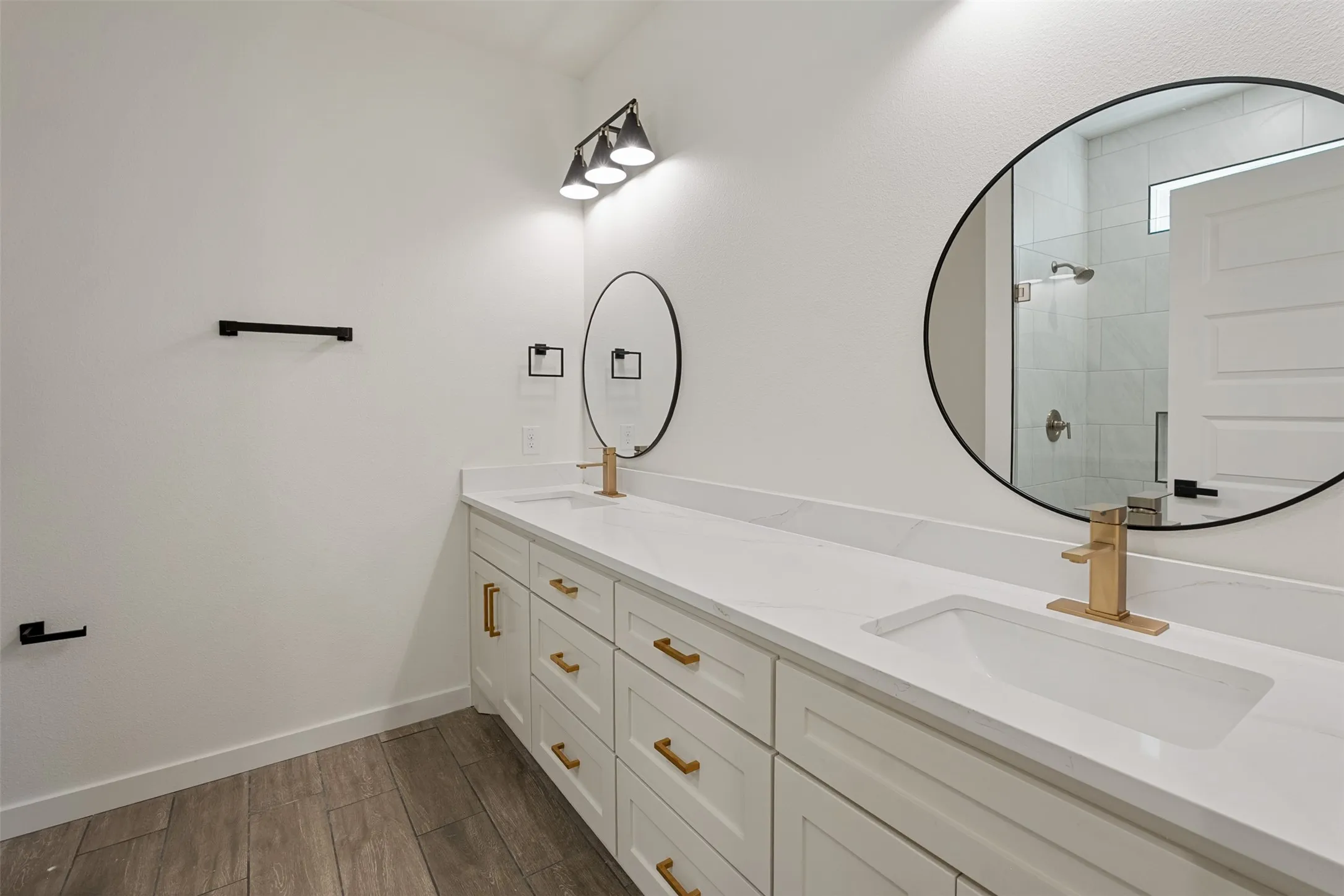Double vanity featuring white cabinetry with gold-tone hardware, integrated undermount sinks, and white countertops