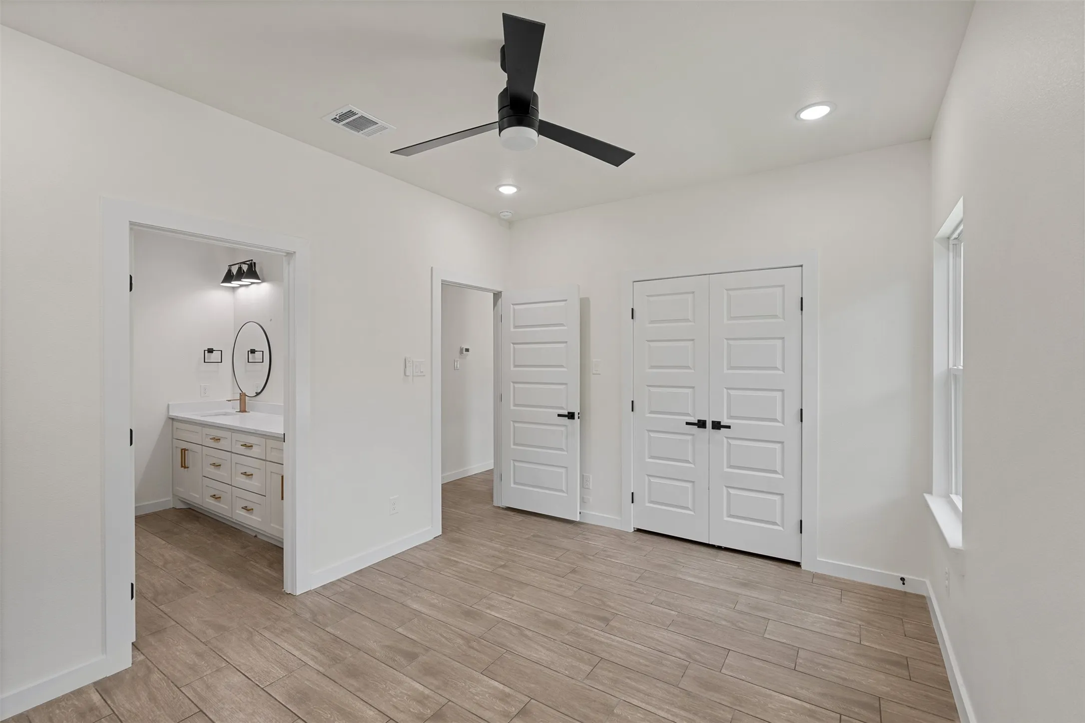 Interior space featuring wood-finish flooring, white walls, and a contemporary black ceiling fan