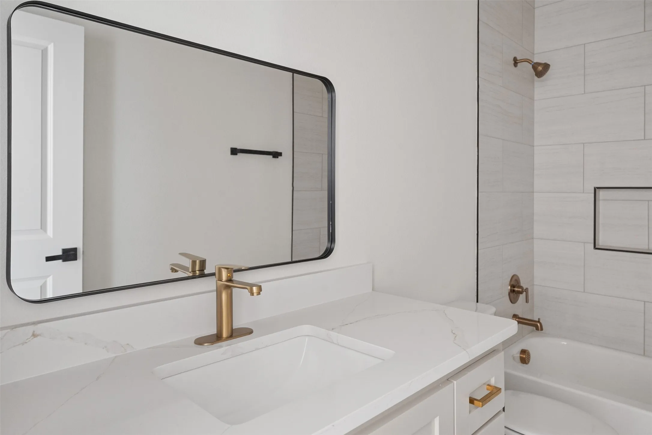 Bathroom vanity featuring a single integrated sink, brass-finish faucet, and white countertop