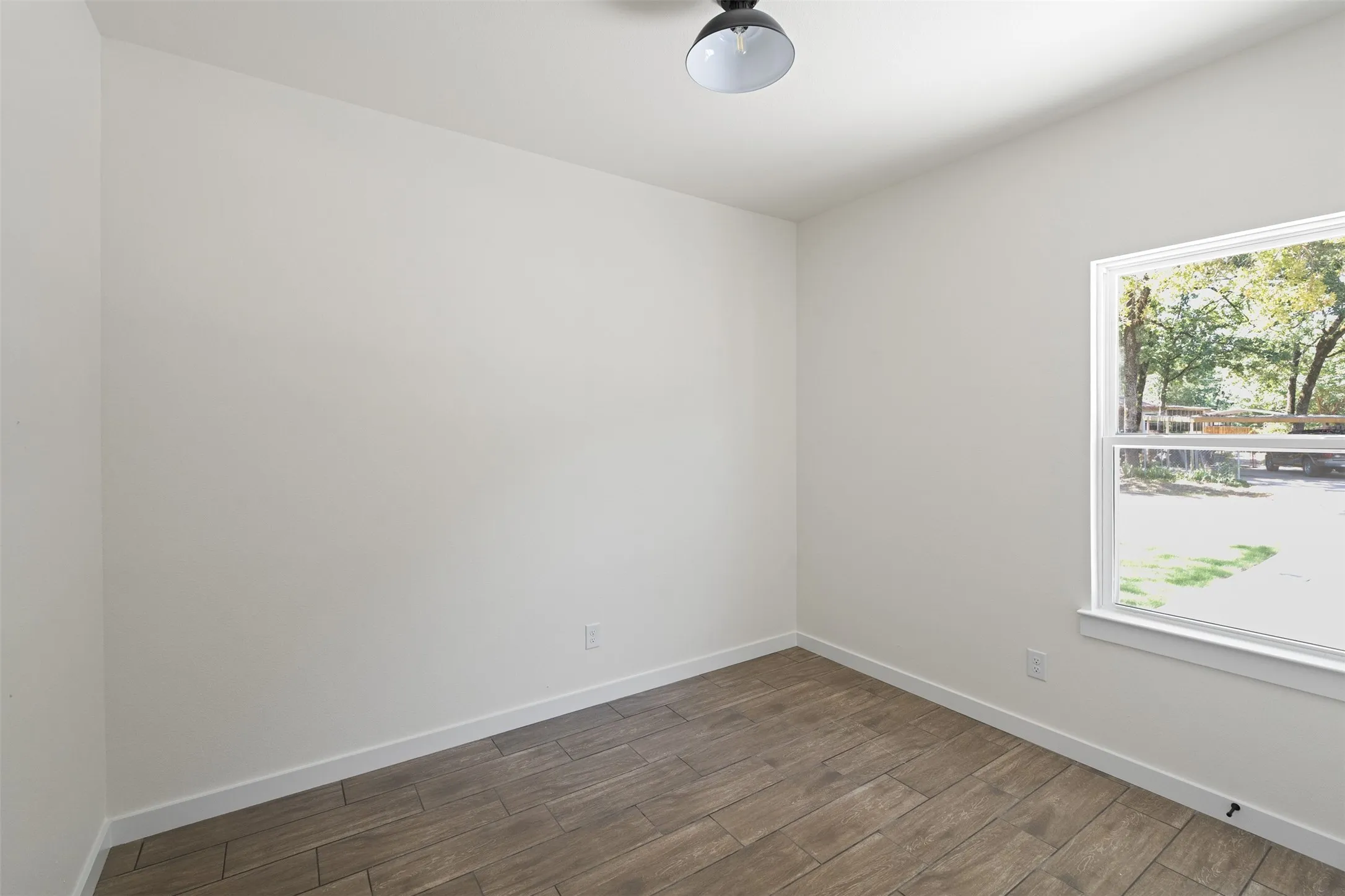 Light-filled room featuring wood-finish flooring, white walls, and a window with outdoor scenery