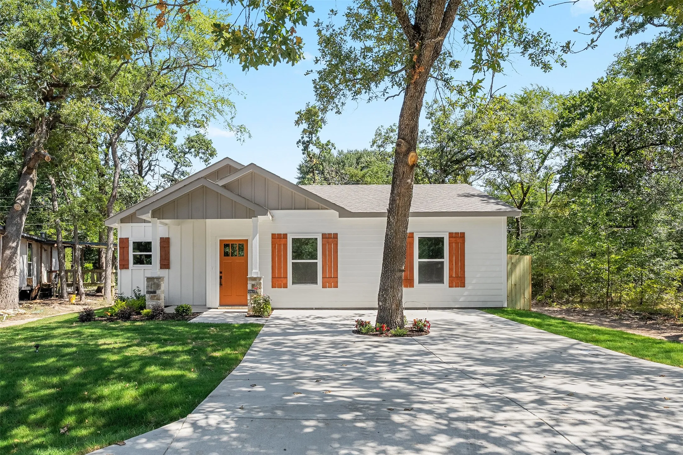 Contemporary exterior with white vertical siding, a covered porch, and an orange entry door