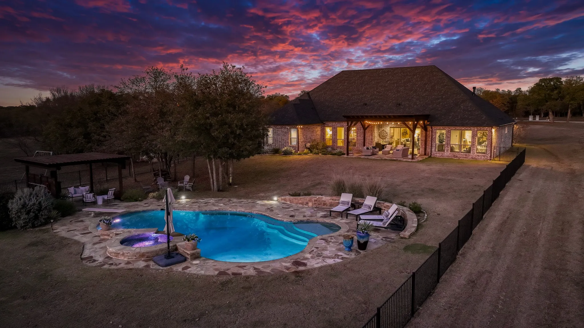 Expansive backyard featuring a freeform swimming pool with integrated spa, surrounded by natural stone coping
