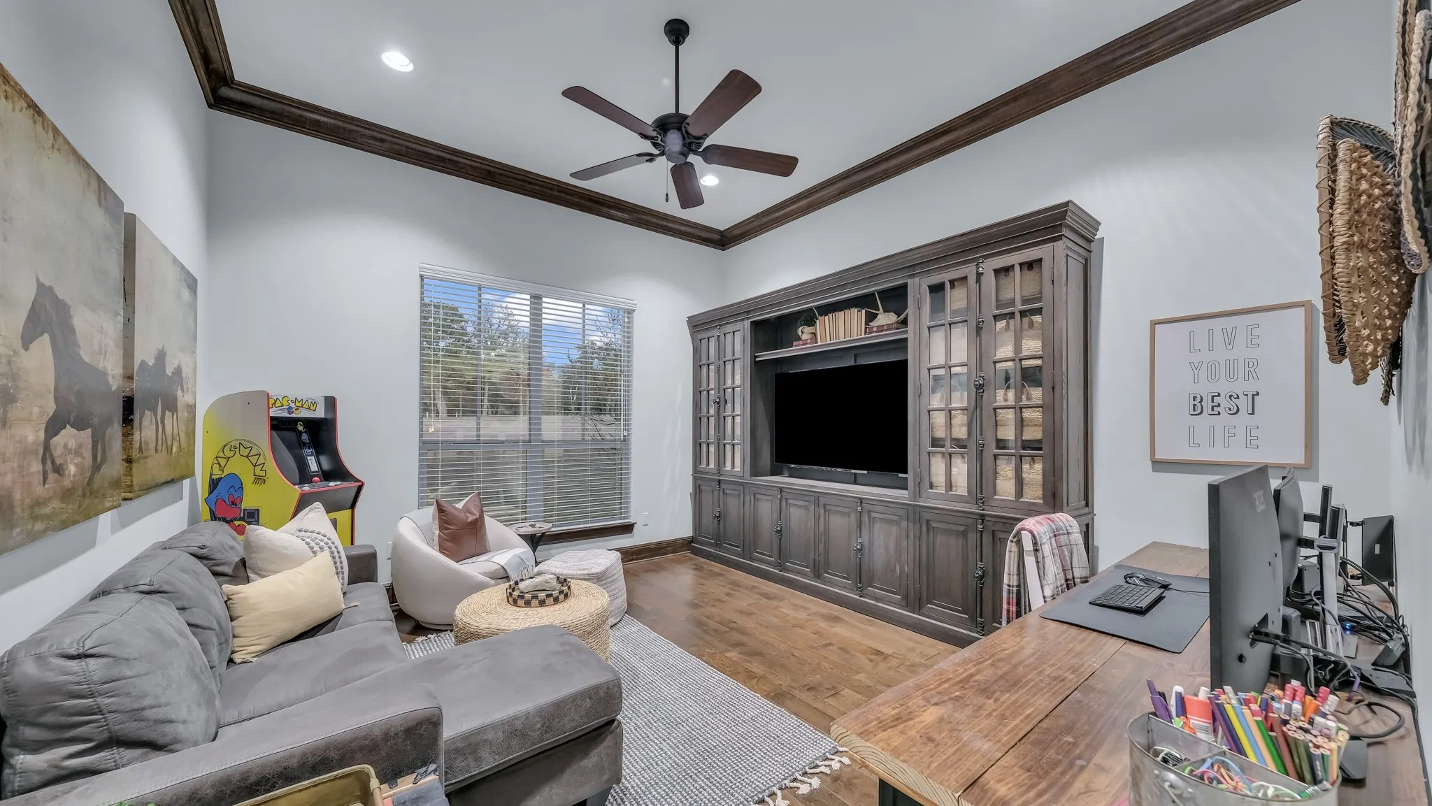 Living area featuring a floor-to-ceiling custom built-in media center with glass-front cabinets, wood-finish flooring, and crown molding