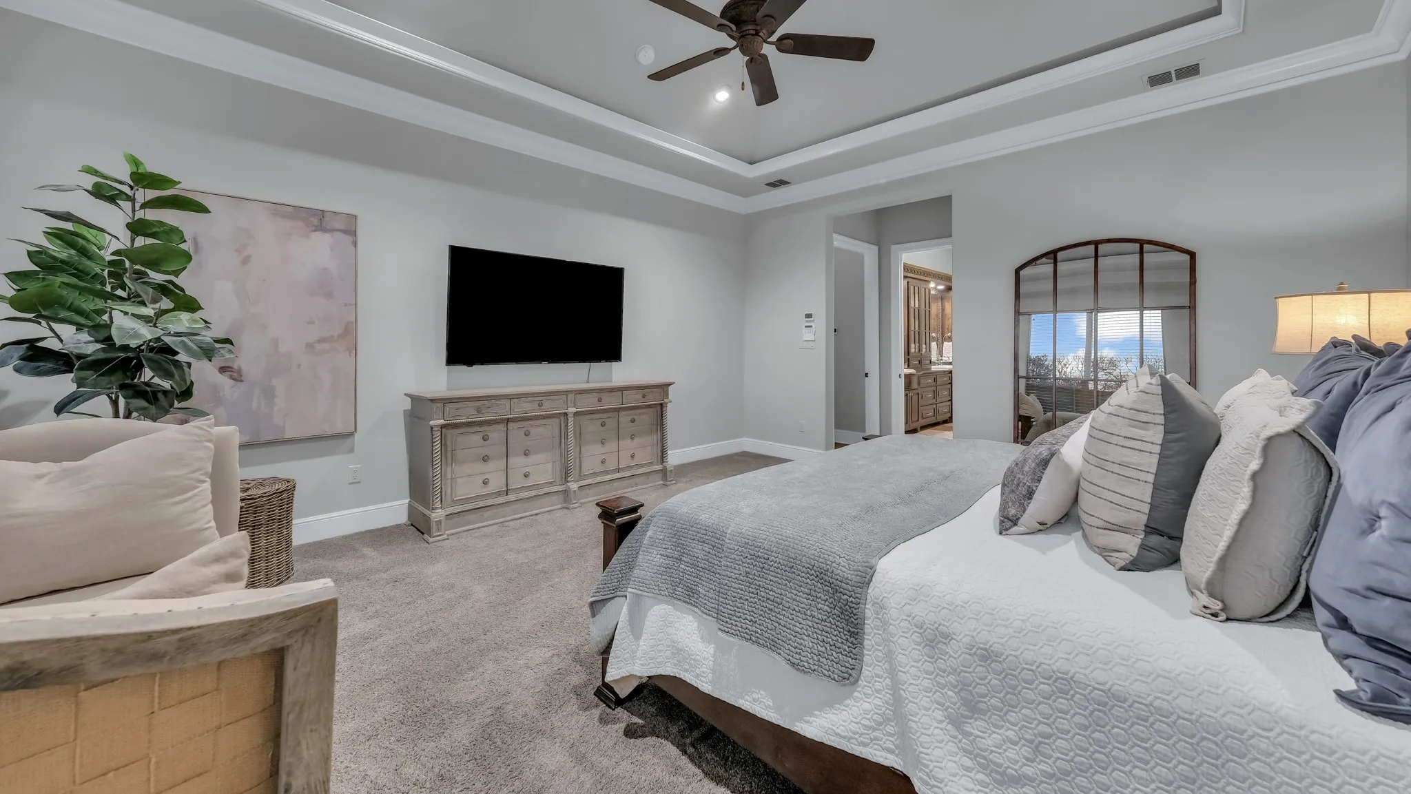 Spacious room featuring tray ceilings with crown molding, recessed lighting, and a ceiling fan