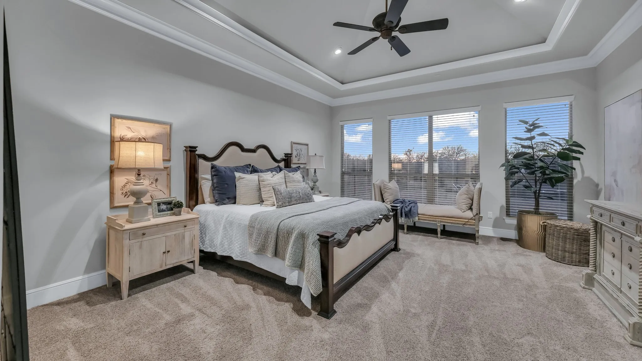 Spacious room featuring tray ceilings with crown molding, recessed lighting, and a ceiling fan