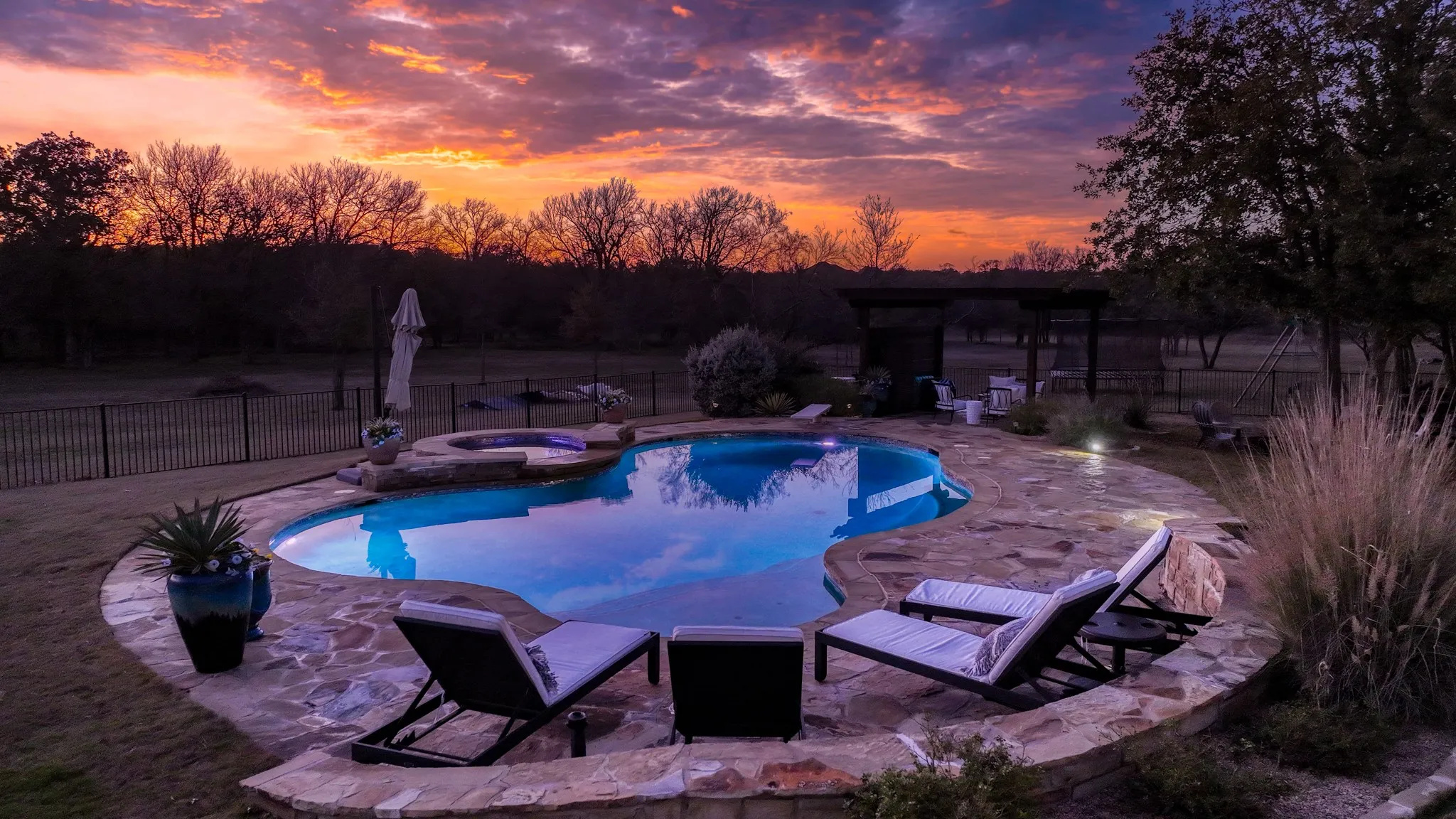 Freeform swimming pool with integrated spa, surrounded by natural stone coping and a flagstone​​‌​​​​‌​​‌‌​‌‌​​​‌‌​‌​‌​‌​​​‌​​ patio