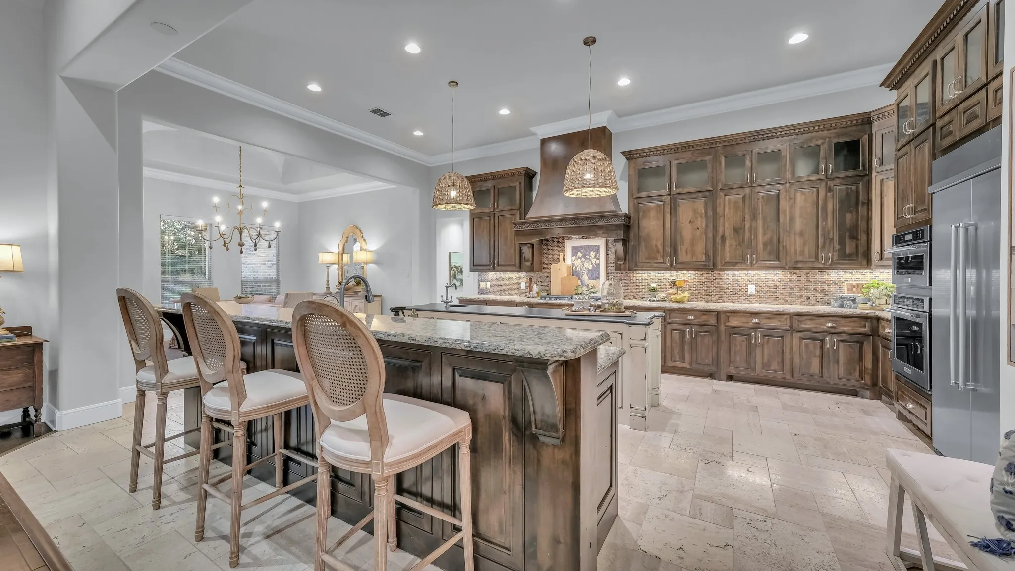Expansive kitchen featuring a double island with granite countertops, stainless steel appliances, custom wood cabinetry, and recessed lighting
