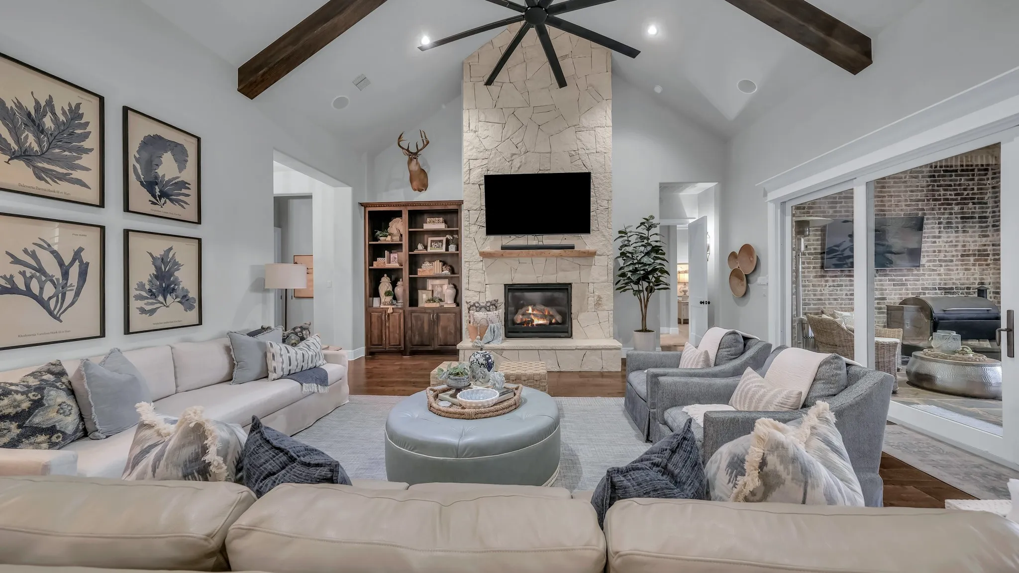 Spacious living area featuring a vaulted ceiling with exposed wood beams, a stone-clad fireplace, and an integrated media niche
