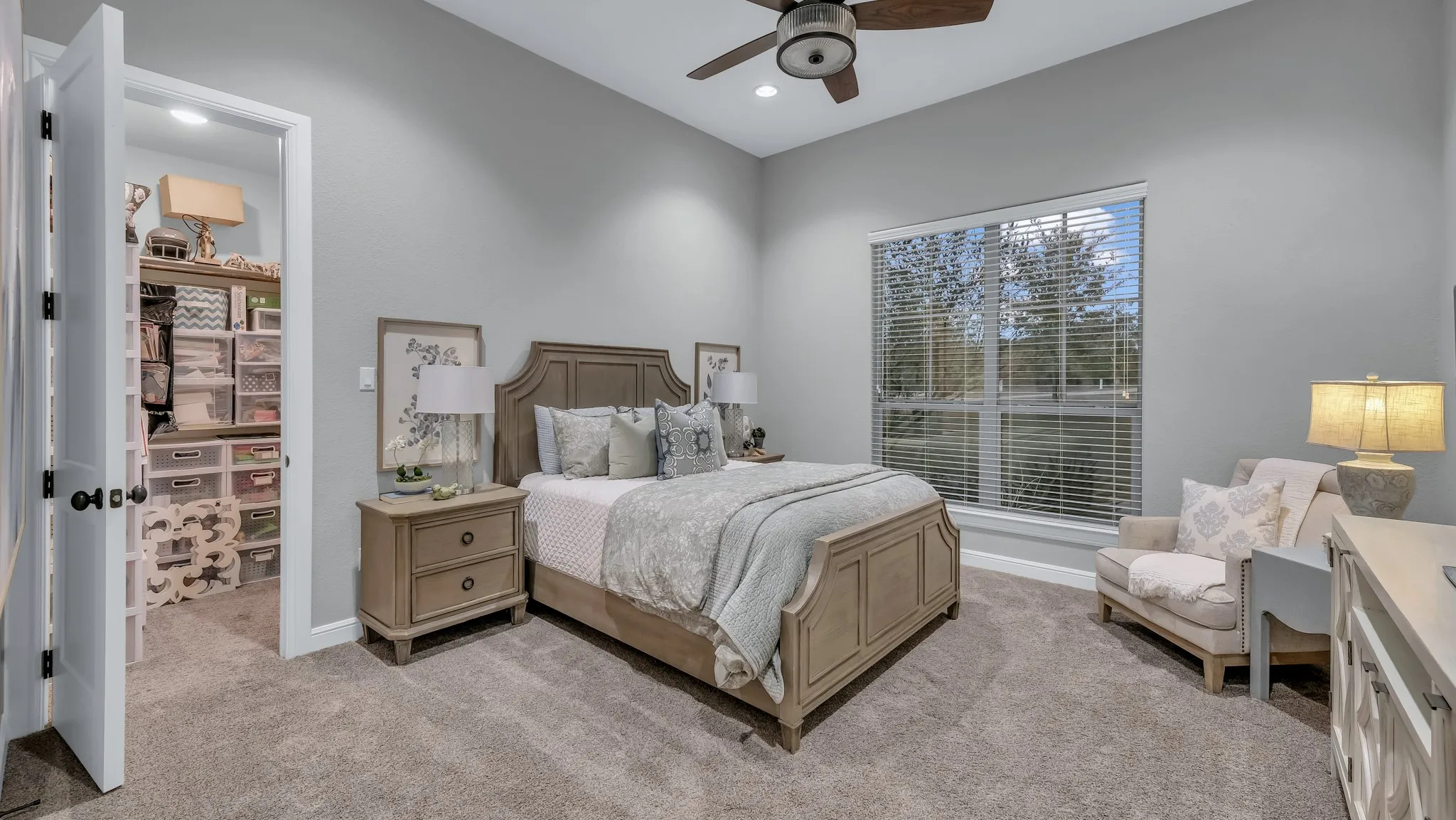 Carpeted bedroom featuring a large window, a ceiling fan, and a built-in closet with shelving