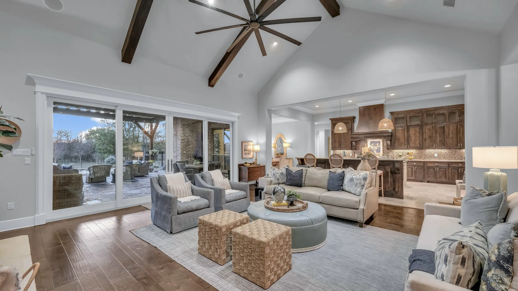 Vaulted living area featuring wood-finish flooring, exposed ceiling beams, and a large ceiling fan