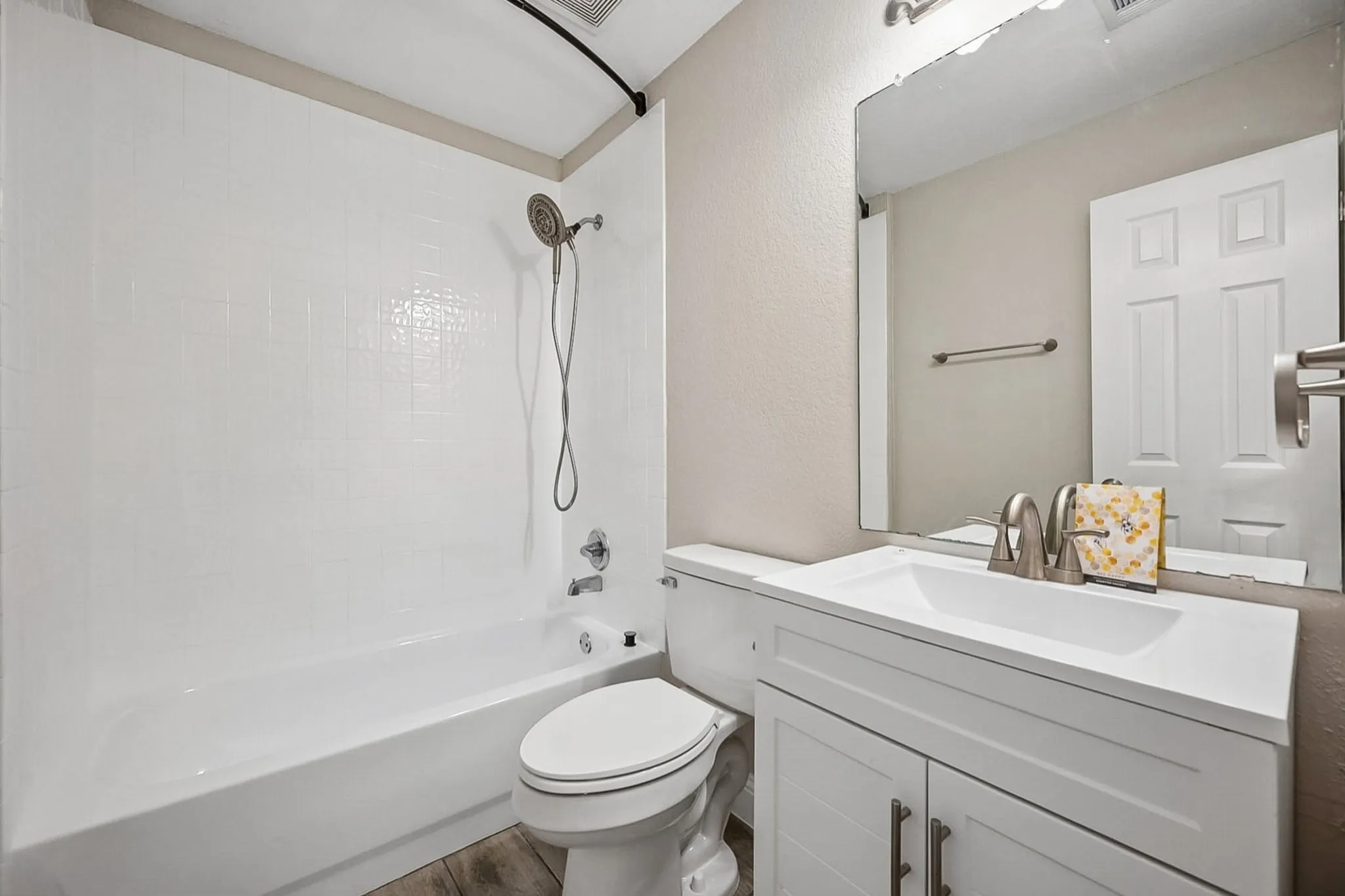 Bathroom featuring a white vanity with shaker-style cabinetry, an integrated sink, and brushed nickel hardware
