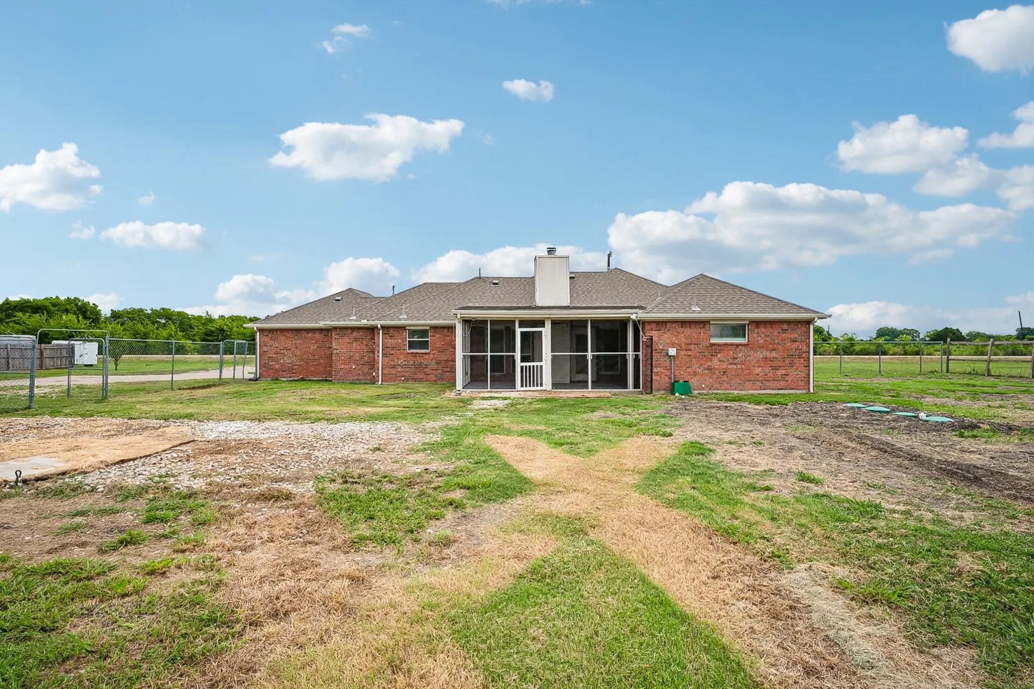 Expansive yard featuring a brick exterior, screened porch, and chain-link fencing
