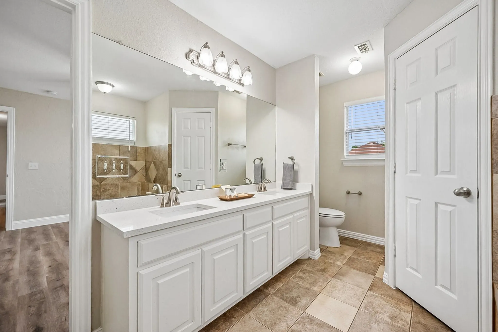 Bathroom featuring a dual-sink vanity with white cabinetry and a light-toned countertop