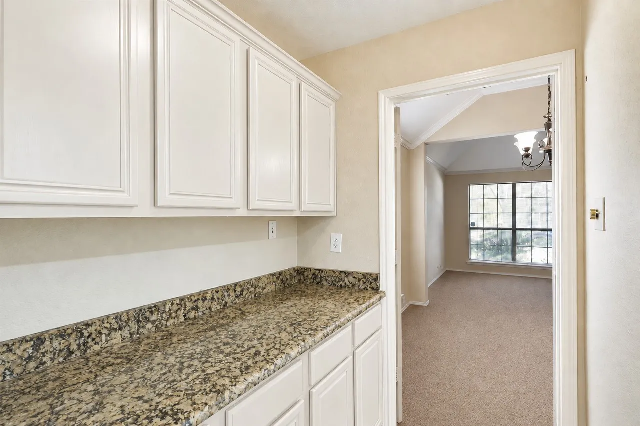 White upper and lower cabinetry, granite-style countertop, and carpeted flooring