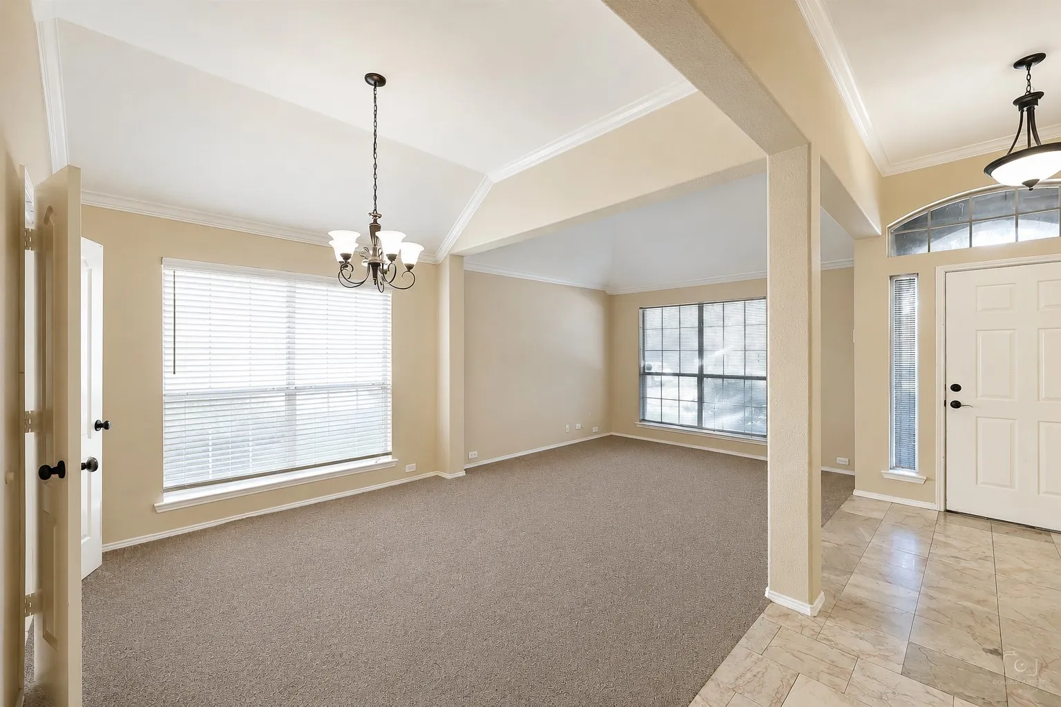 Carpeted living area with vaulted ceiling and crown molding