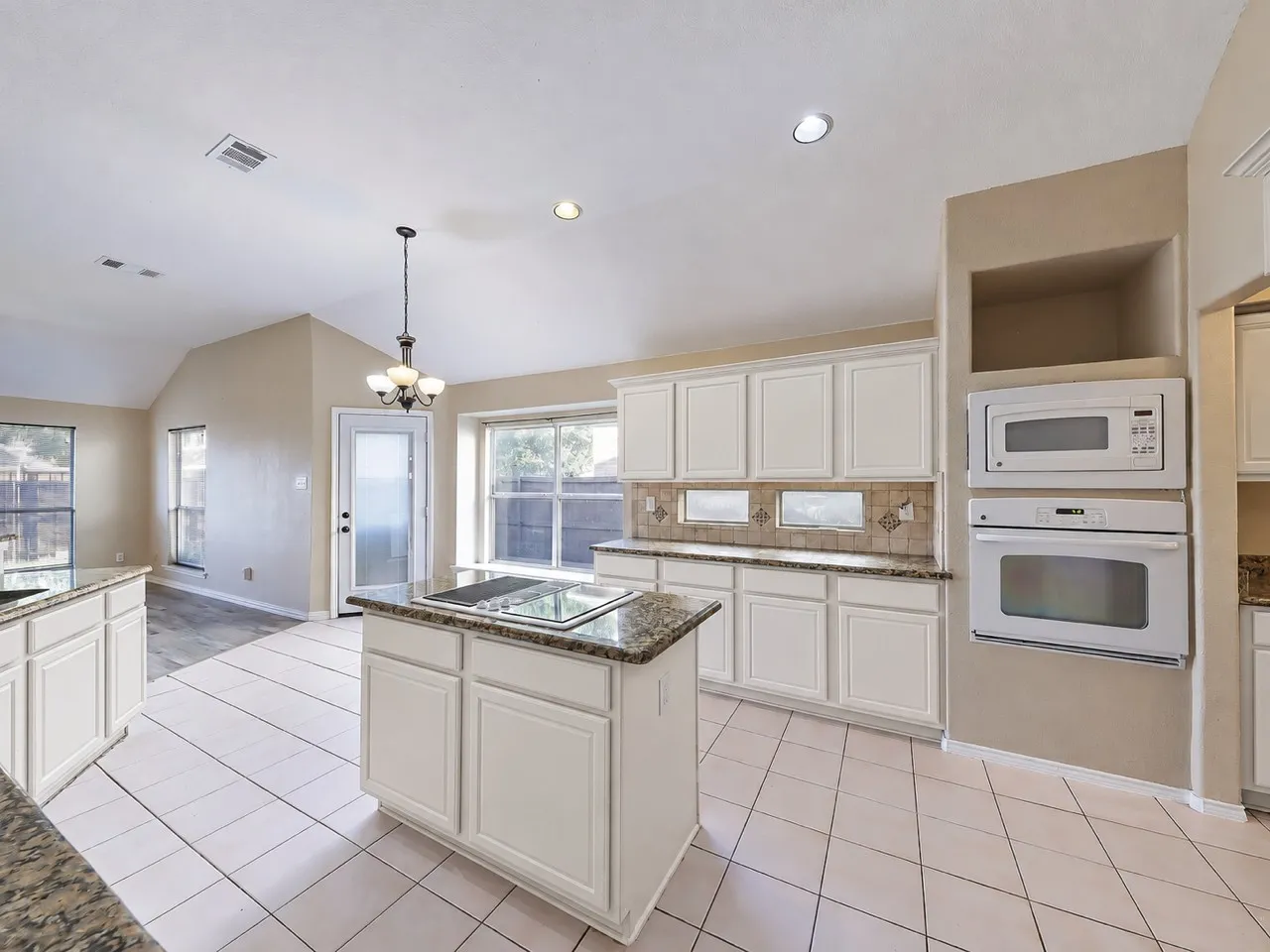 Kitchen featuring white cabinetry, built-in wall oven and microwave, stone-finish countertops, and a tiled backsplash