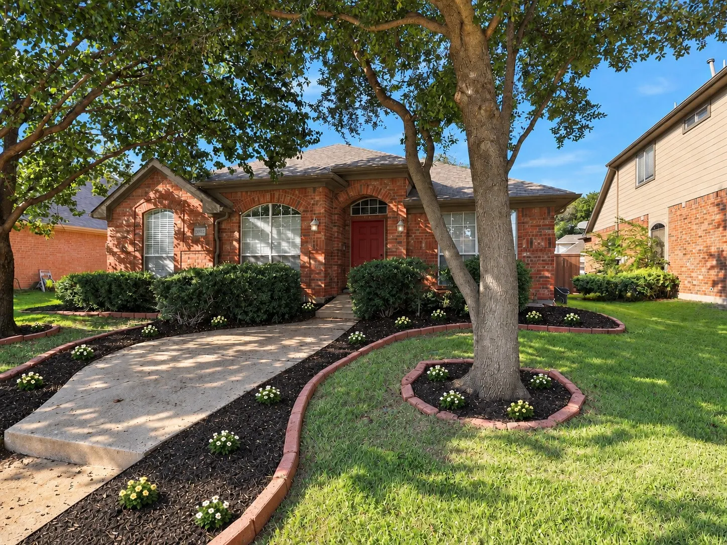 Brick facade residence with an arched entryway and a prominent red front door