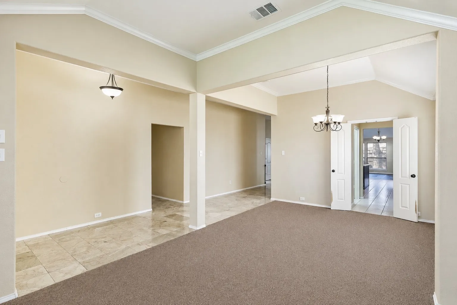 Expansive interior space featuring vaulted ceilings, crown molding, and a chandelier lighting fixture