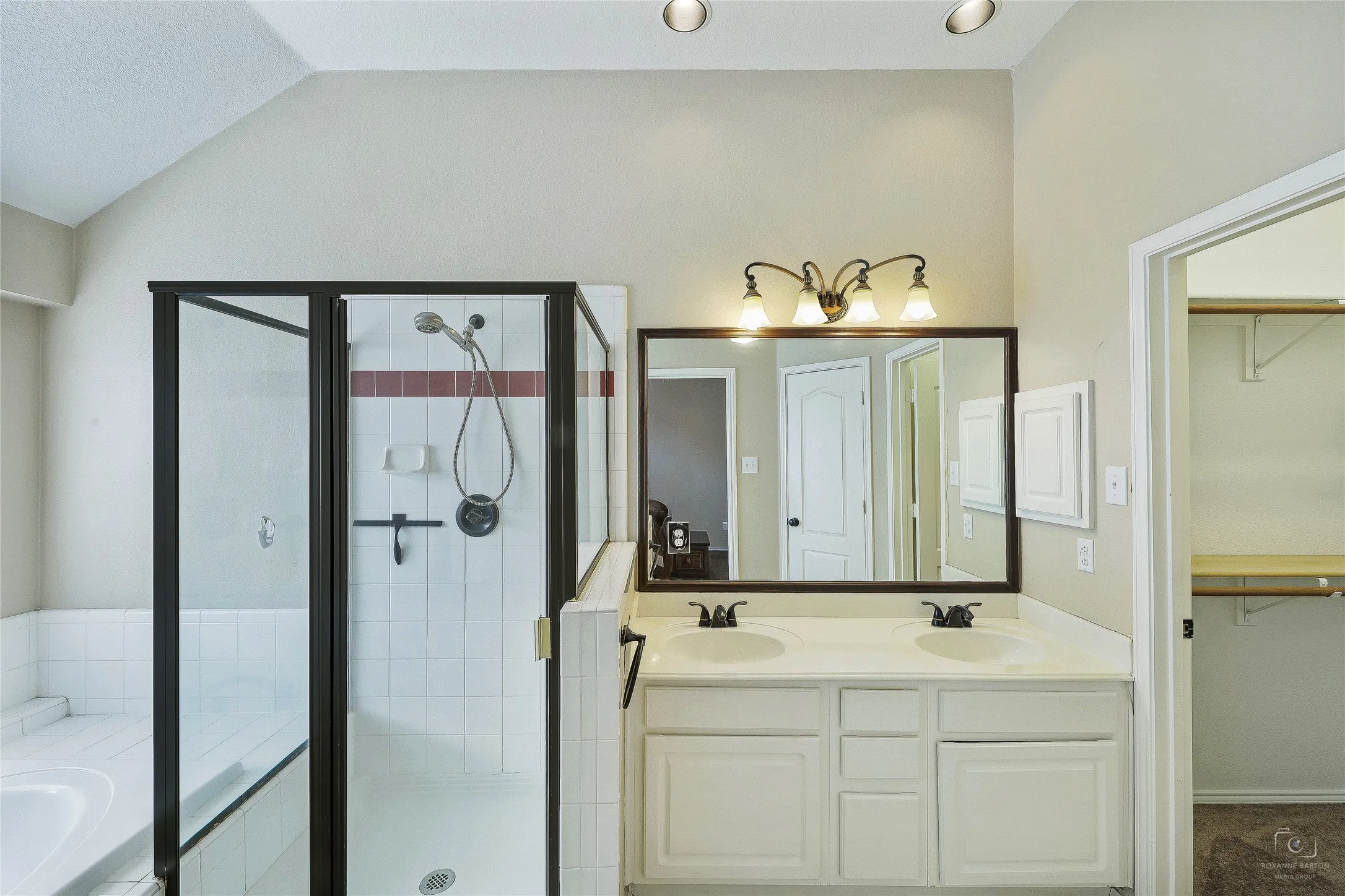 Bathroom featuring a dual vanity with white cabinetry and a large framed mirror