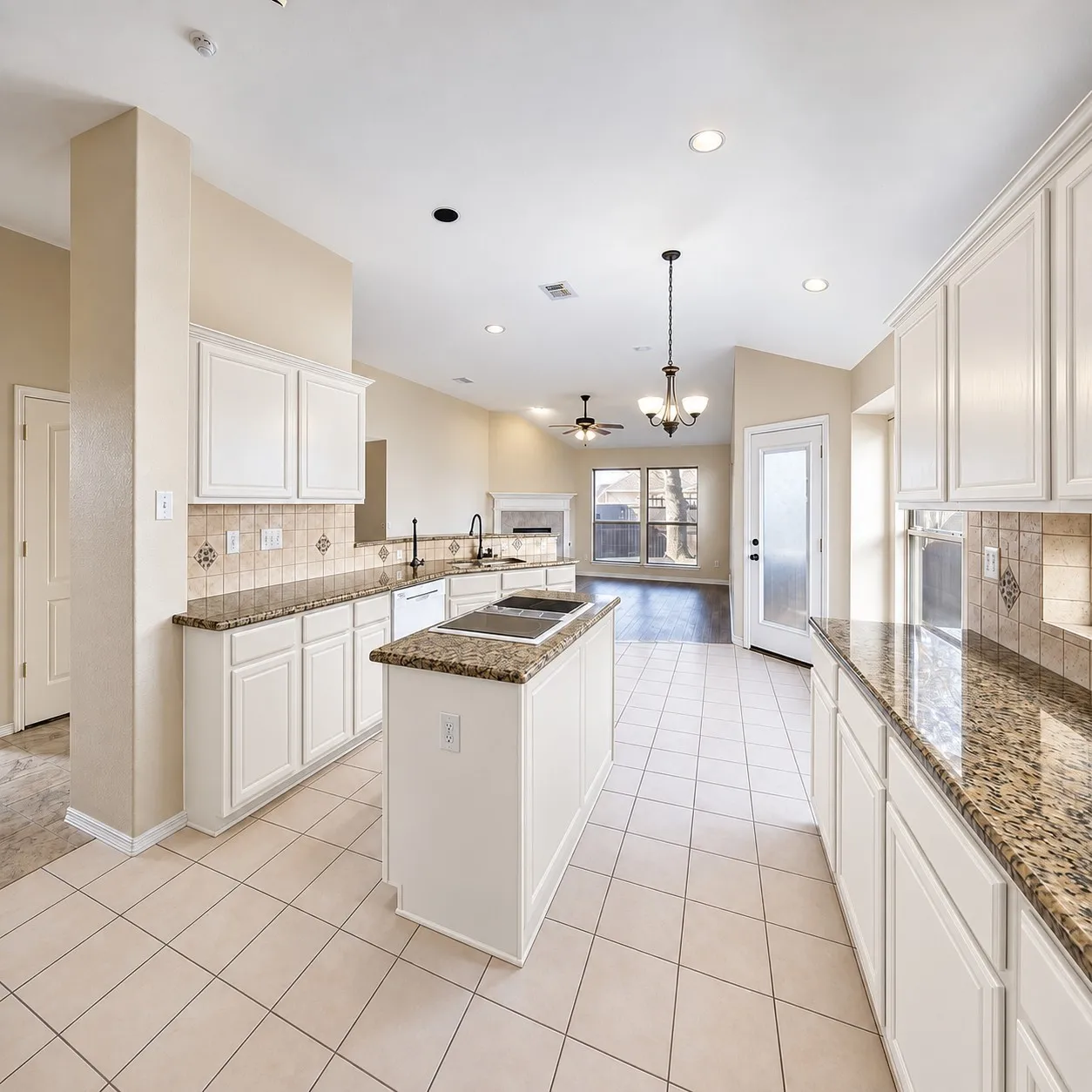 Kitchen featuring an island with built-in cooktop, white cabinetry, granite countertops, tile backsplash, and tile flooring
