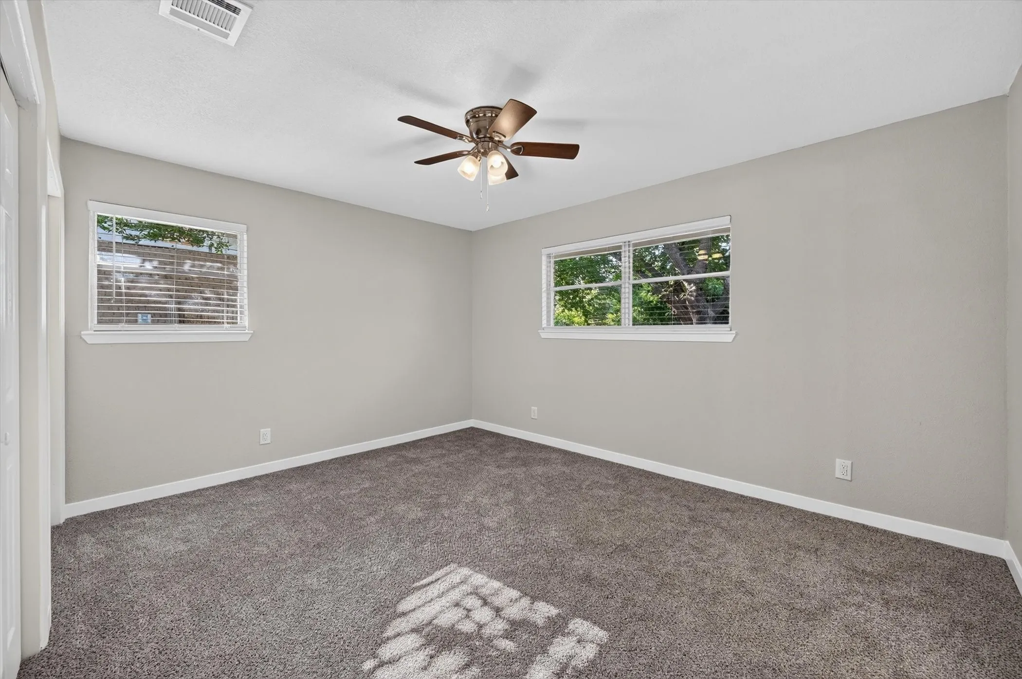 Bedroom featuring light gray walls, gray carpet, and two windows with white blinds