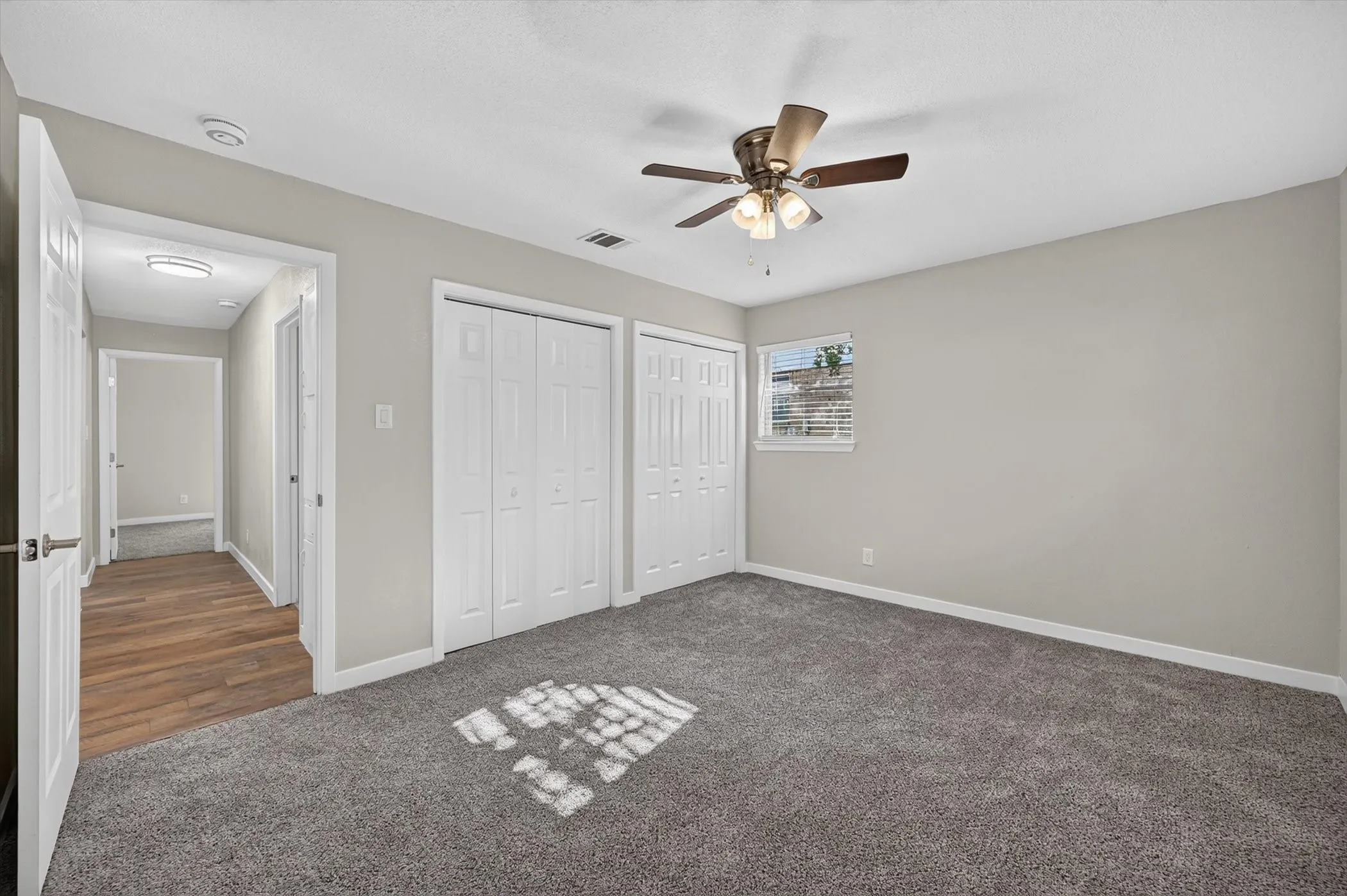 Spacious room with gray textured carpeting and light gray walls