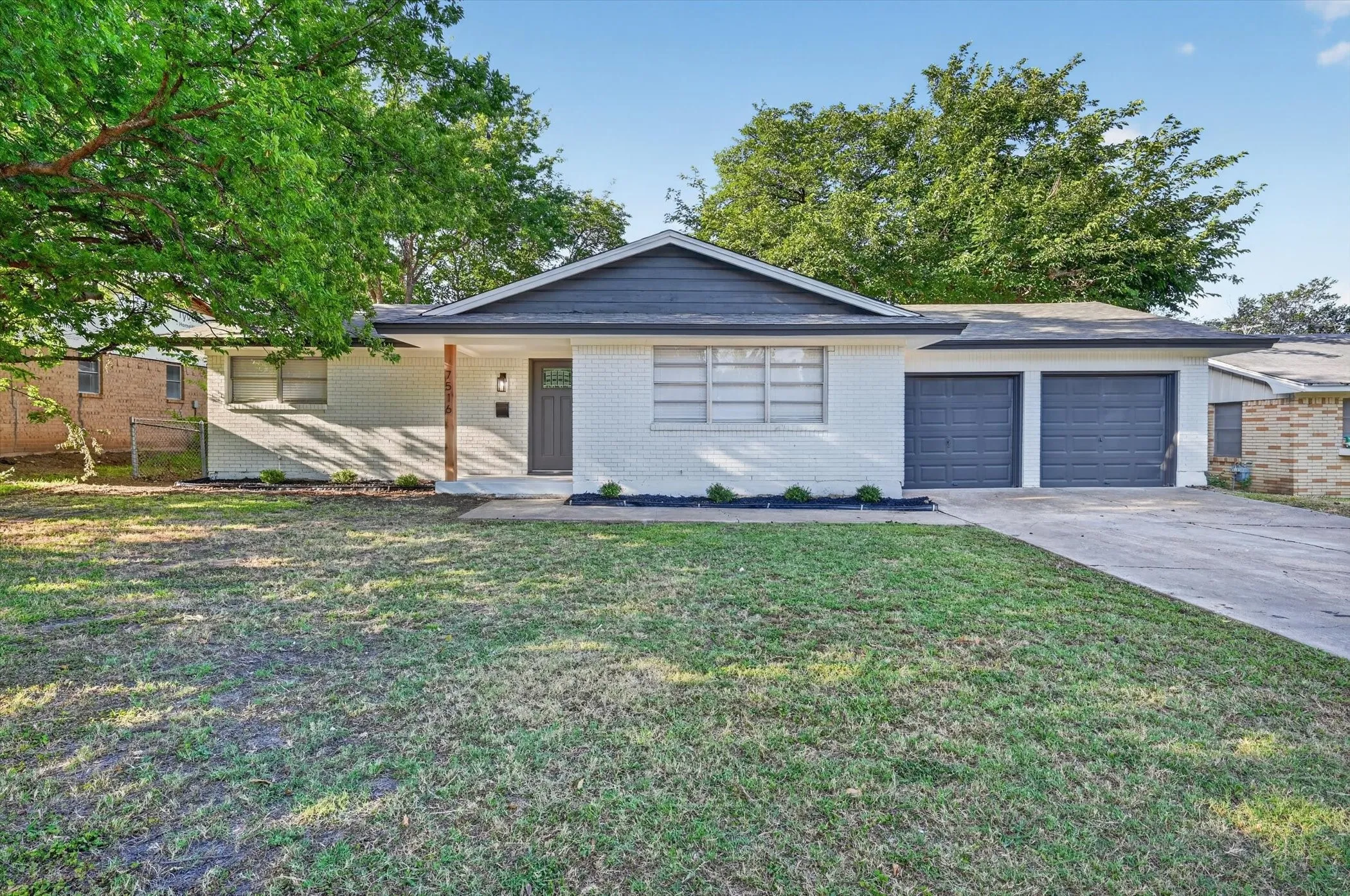 Contemporary ranch-style home featuring a white brick facade and a dark gray roofline