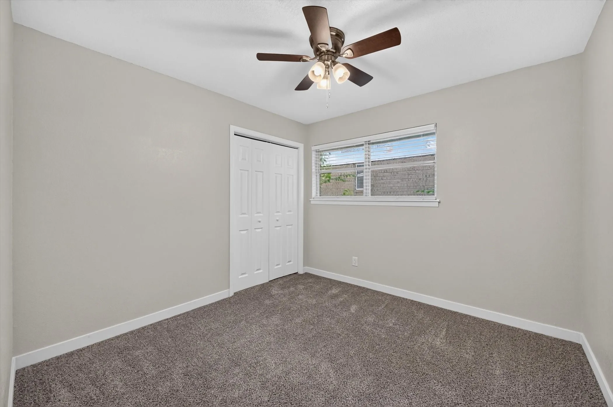 Carpeted interior room with light gray walls, white trim, and a white bi-fold closet door