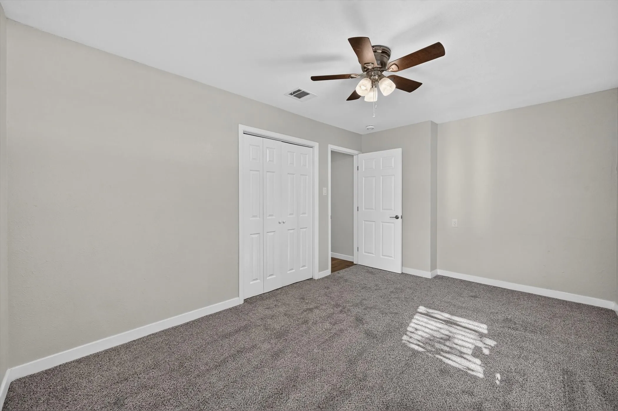 Spacious room featuring gray carpet flooring, light gray wall paint, and white trim
