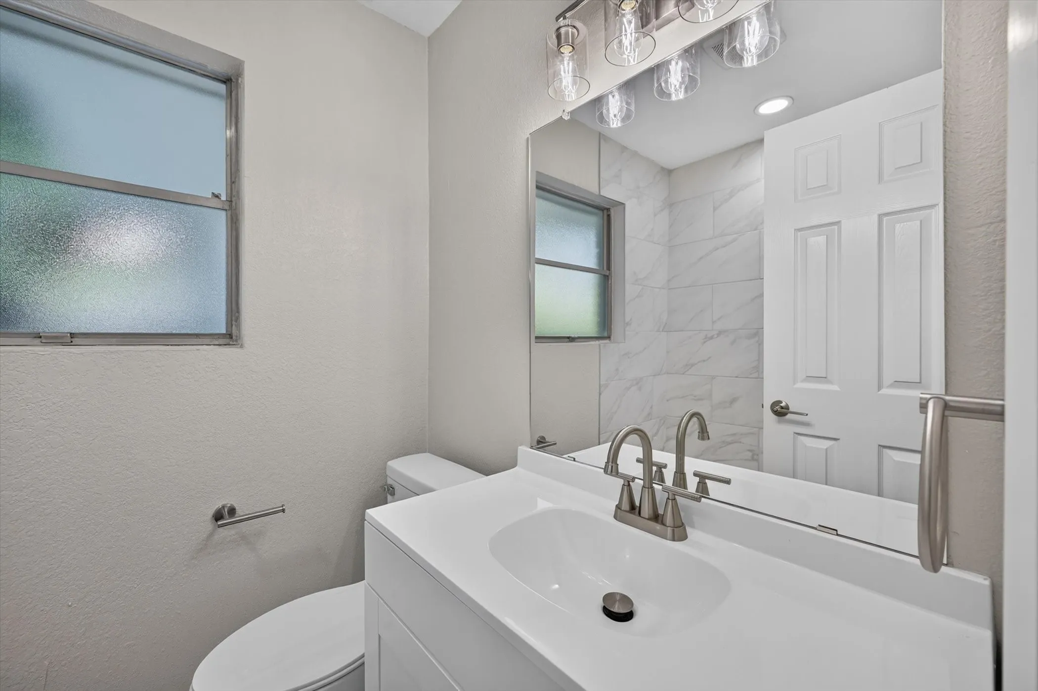 Bathroom vanity featuring a white integrated sink and brushed nickel faucet