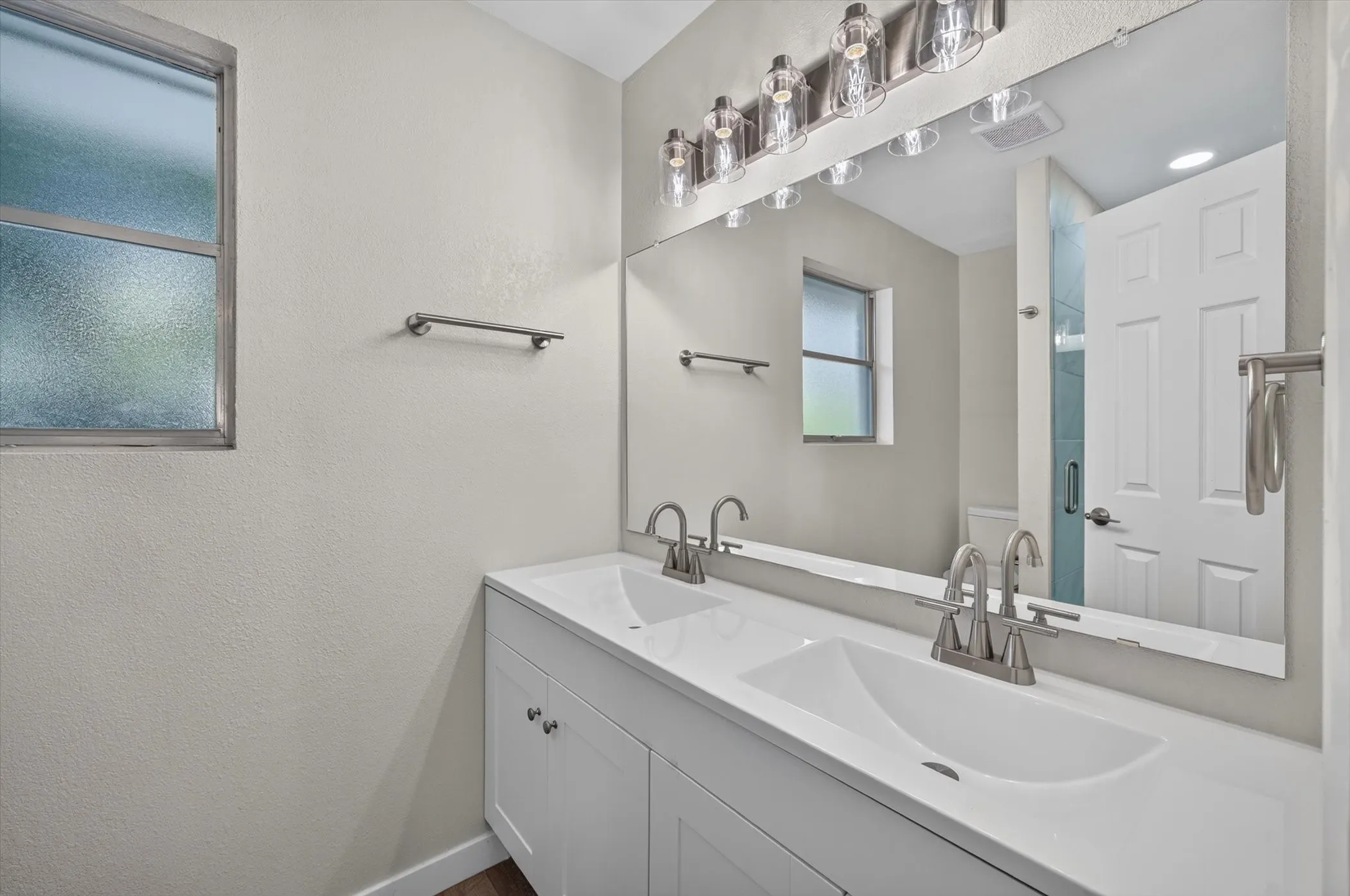 Dual vanity featuring integrated sinks, white cabinetry, and brushed nickel hardware