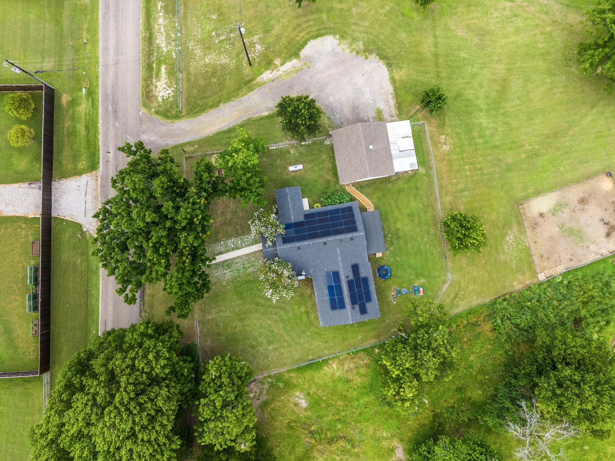 Expansive property featuring a main residence with solar panels, a secondary detached structure, and a large grassy yard