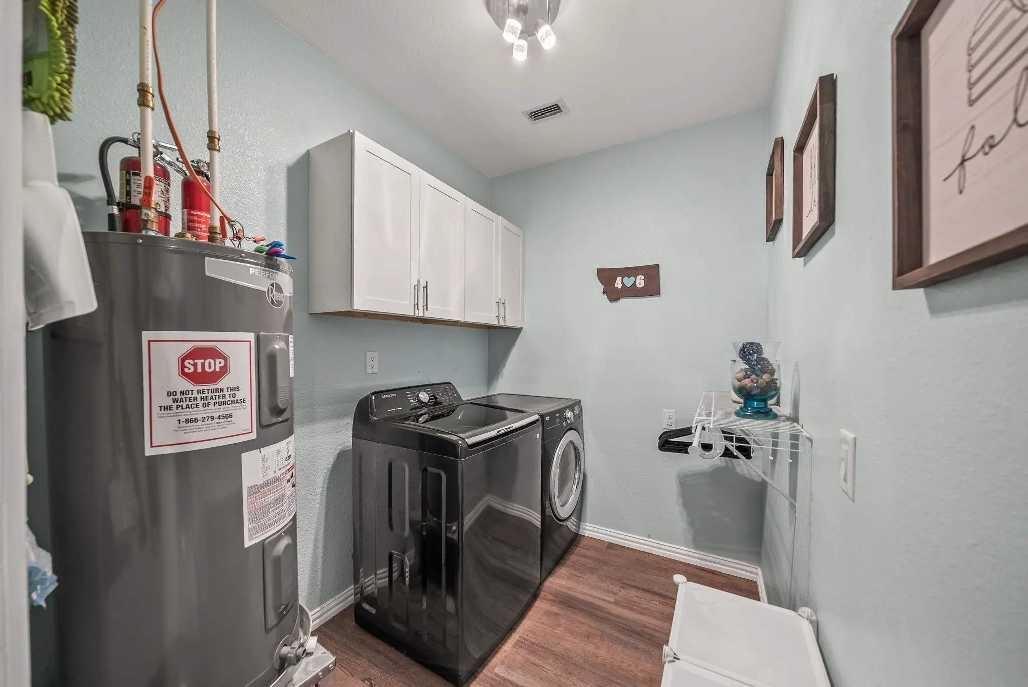 Dedicated utility space featuring a water heater, wood-finish flooring, and light blue walls