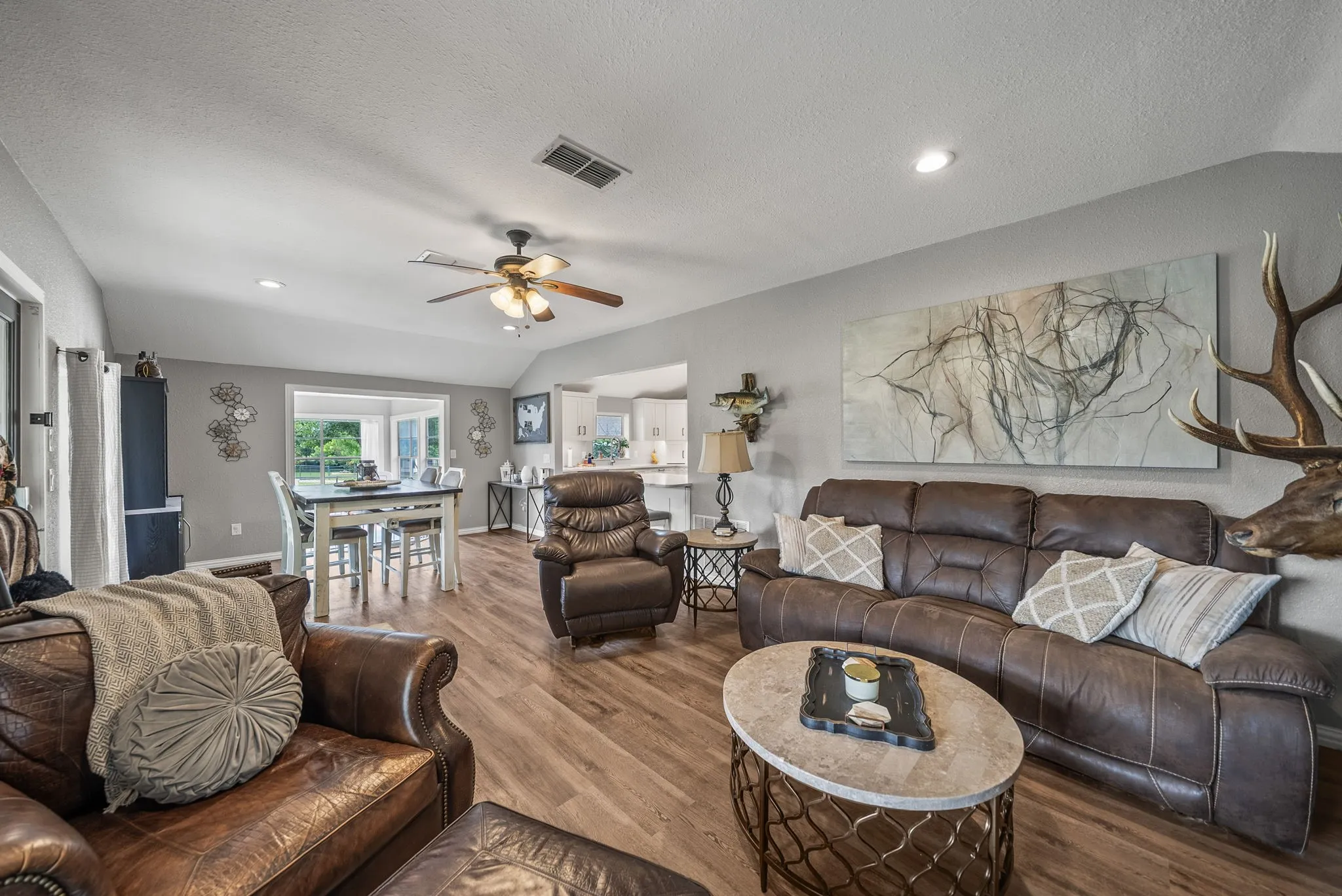 Spacious living area featuring wood-finish flooring, vaulted ceilings, recessed lighting, and a ceiling fan