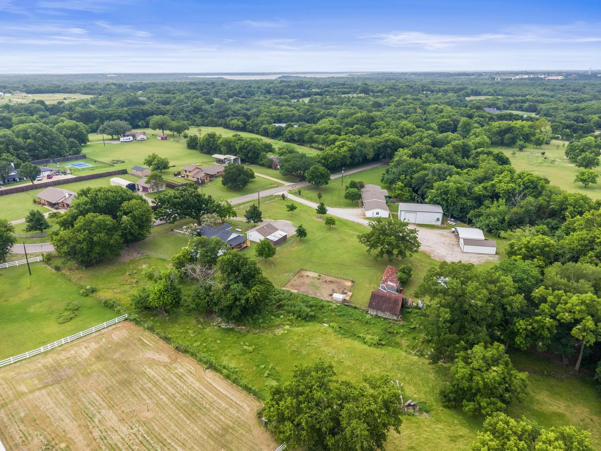 Expansive aerial showcasing a verdant landscape with mature trees, multiple residential structures, and various outbuildings