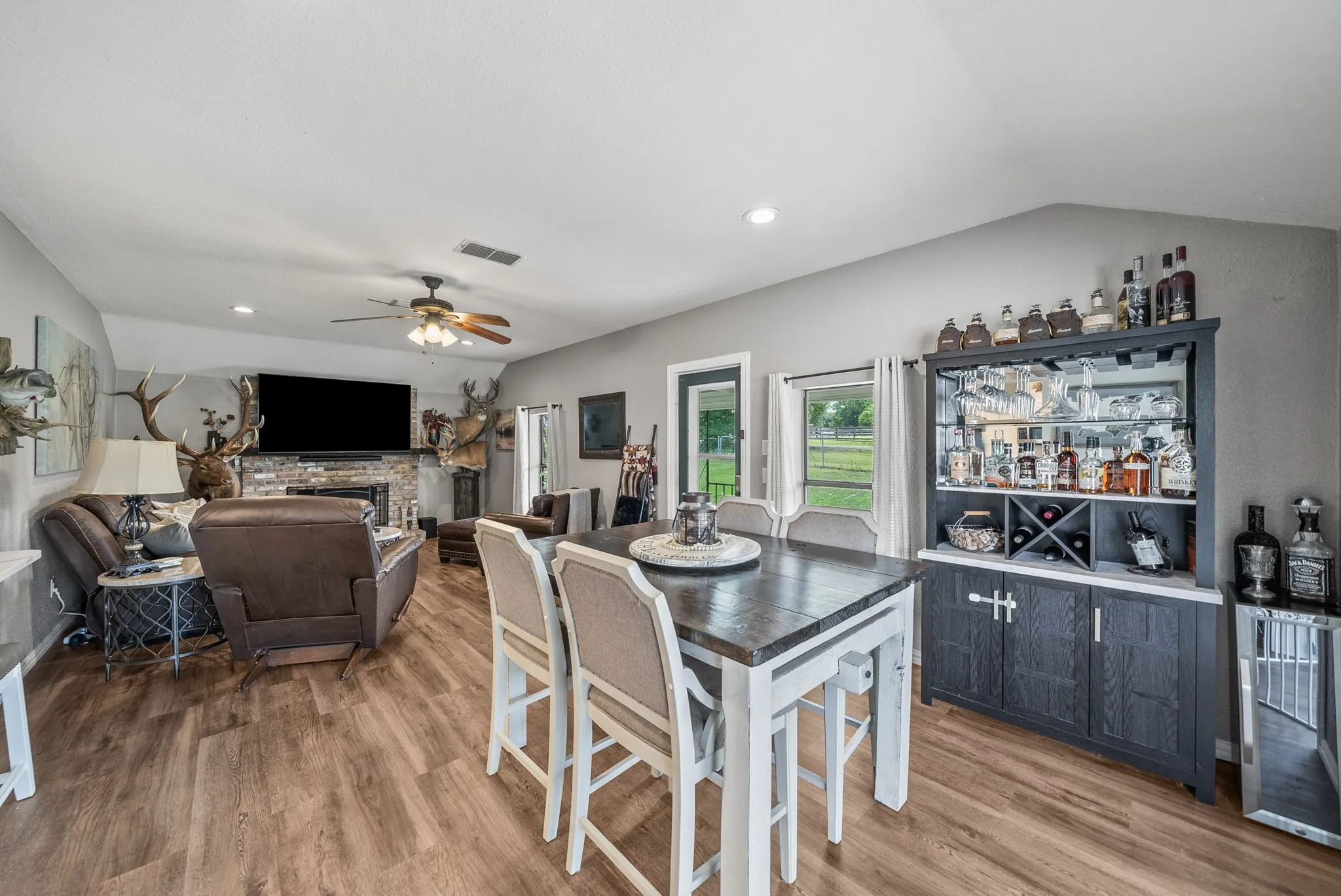 Open-concept living space featuring wood-finish flooring, a stone-faced fireplace, and vaulted ceilings