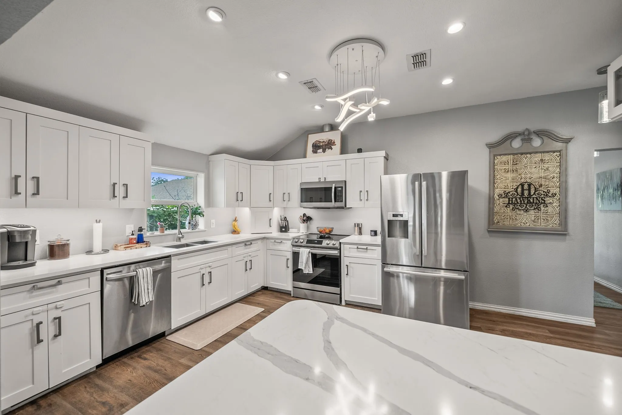 Kitchen featuring white shaker cabinetry, stainless steel appliances, white countertops, and wood-finish flooring