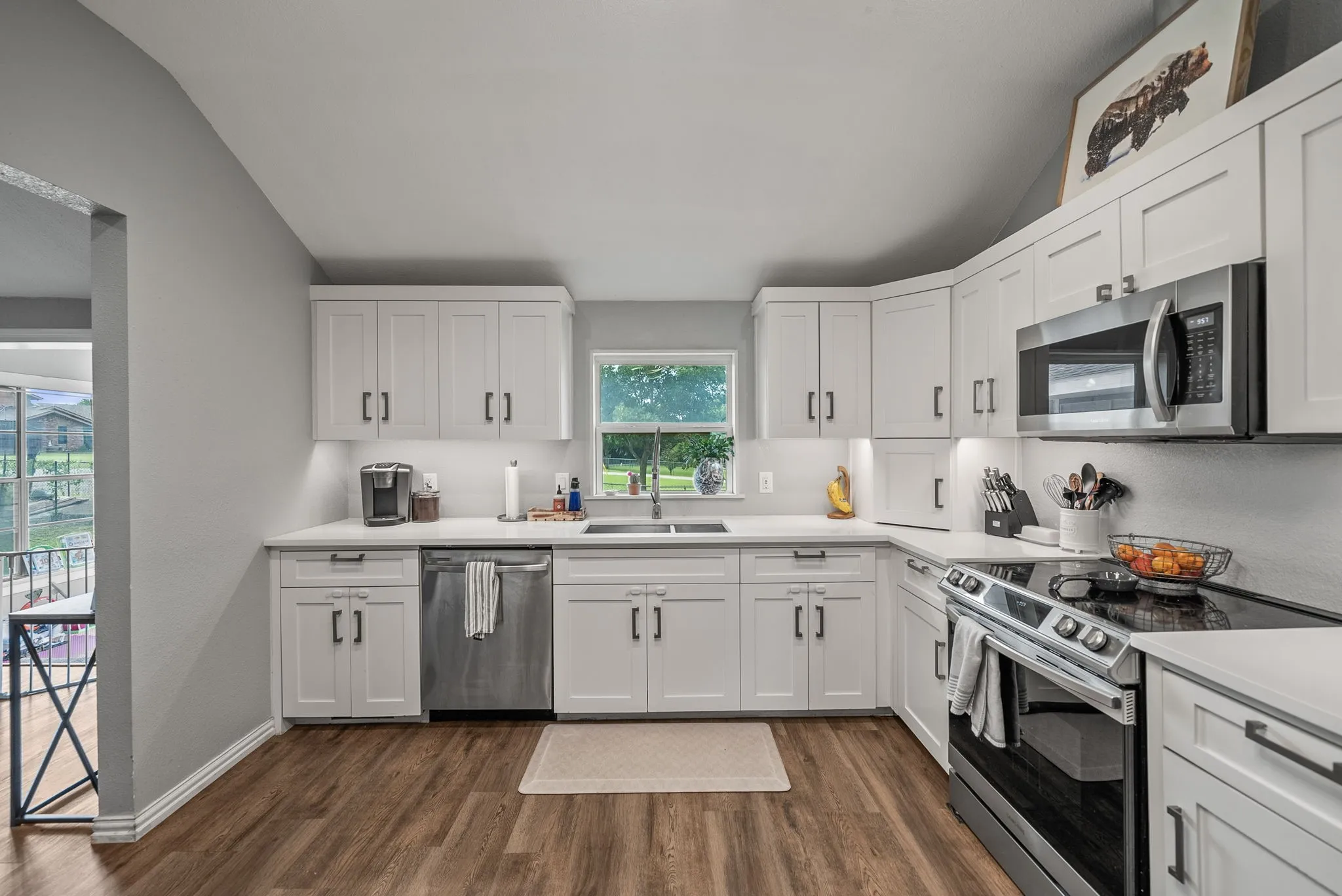 Kitchen featuring white shaker-style cabinetry, stainless steel appliances, white countertops, and wood-finish flooring