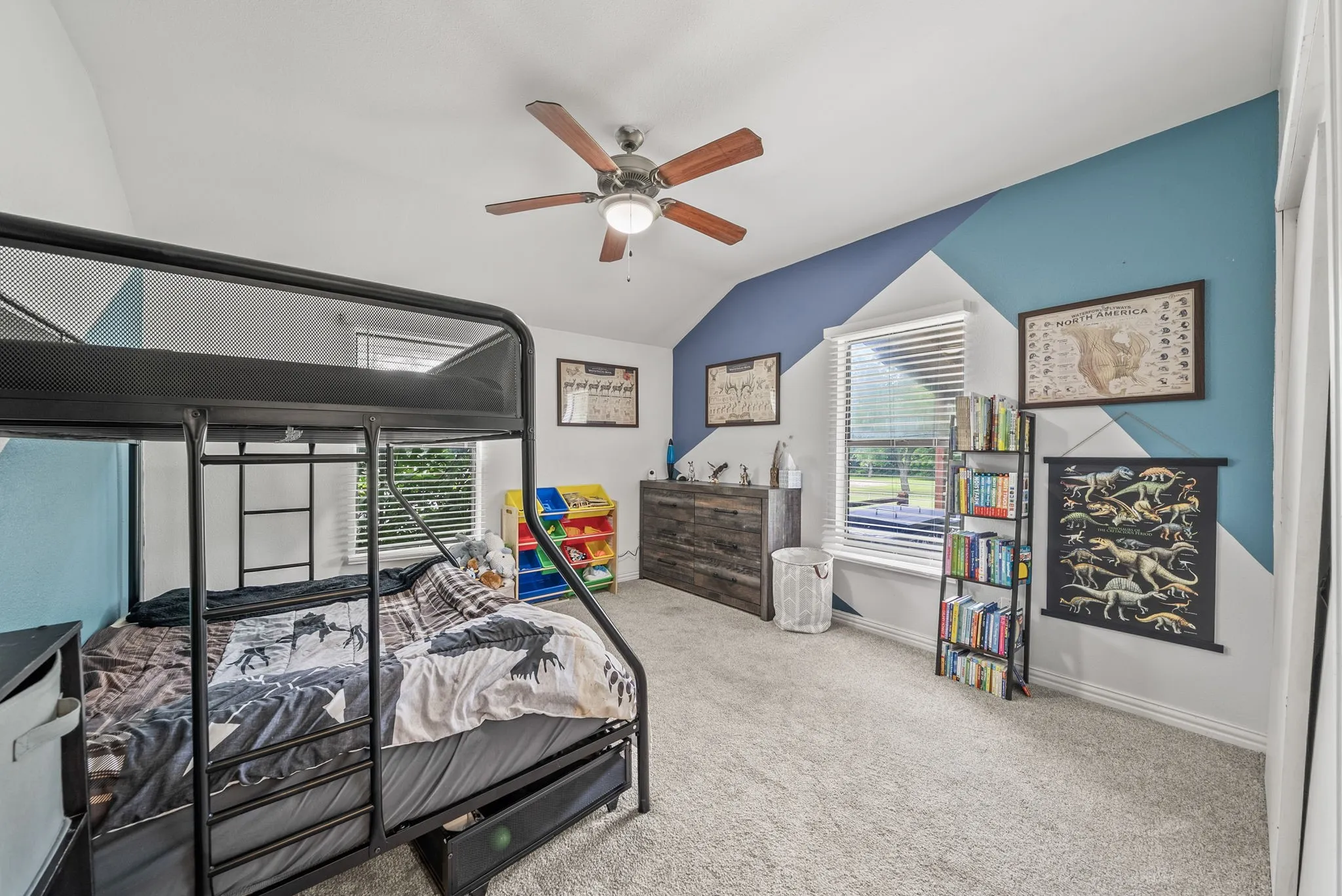 Bright room featuring sloped ceilings, a ceiling fan, and carpet flooring