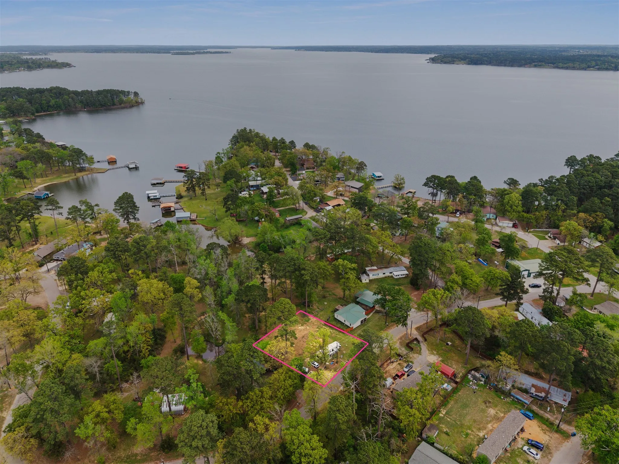 Aerial perspective showcasing a property outlined in pink, surrounded by mature trees